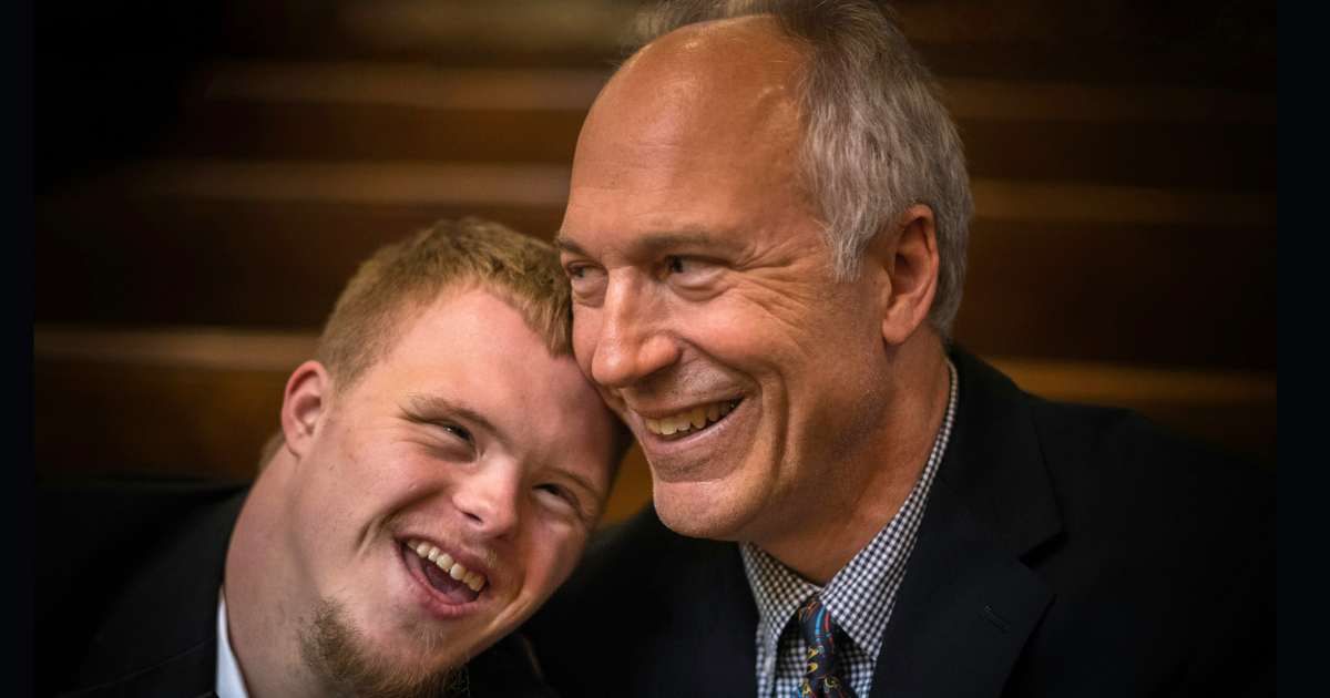 Dad embraces grown up son with down syndrome with a proud smile. (Representative Cover Image Source: Unsplash| Nathan Anderson)
