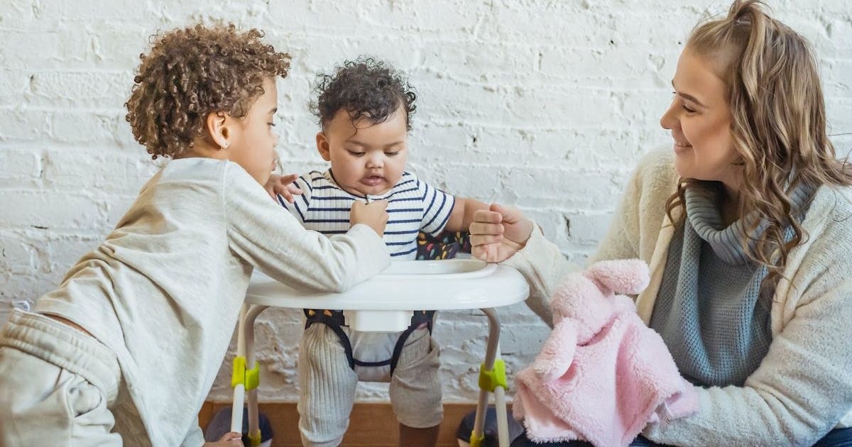 Toddler in a walker standing close to his mom and older sibling. Representative Cover Image Source: Getty Images | Keira Burton