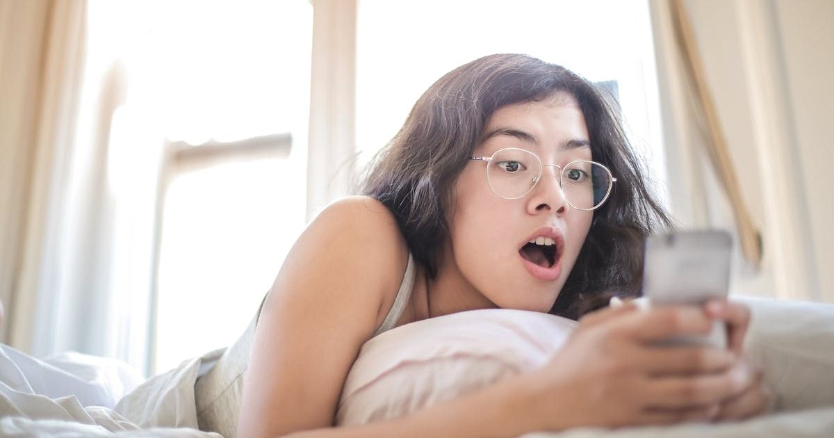 Woman in bed looking at phone with a surprised expression. Representative Cover Image Source: Pexels | Andrea Piacquadio