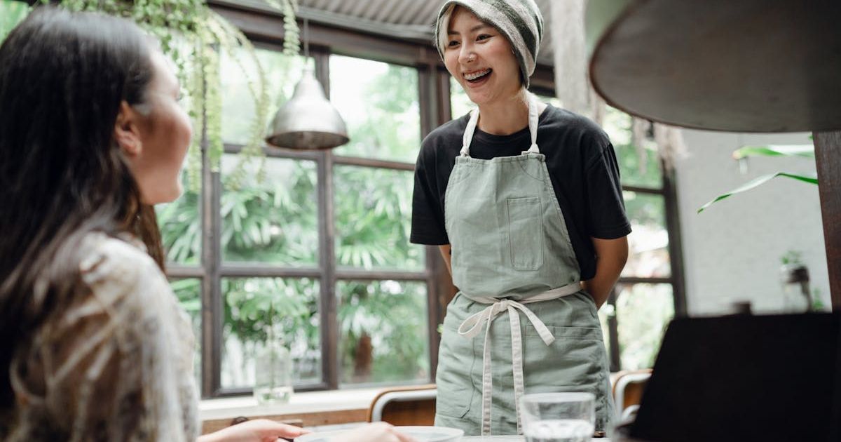 Server smiling at a customer. Representative Cover Image Source: Pexels | Ketut Subiyanto