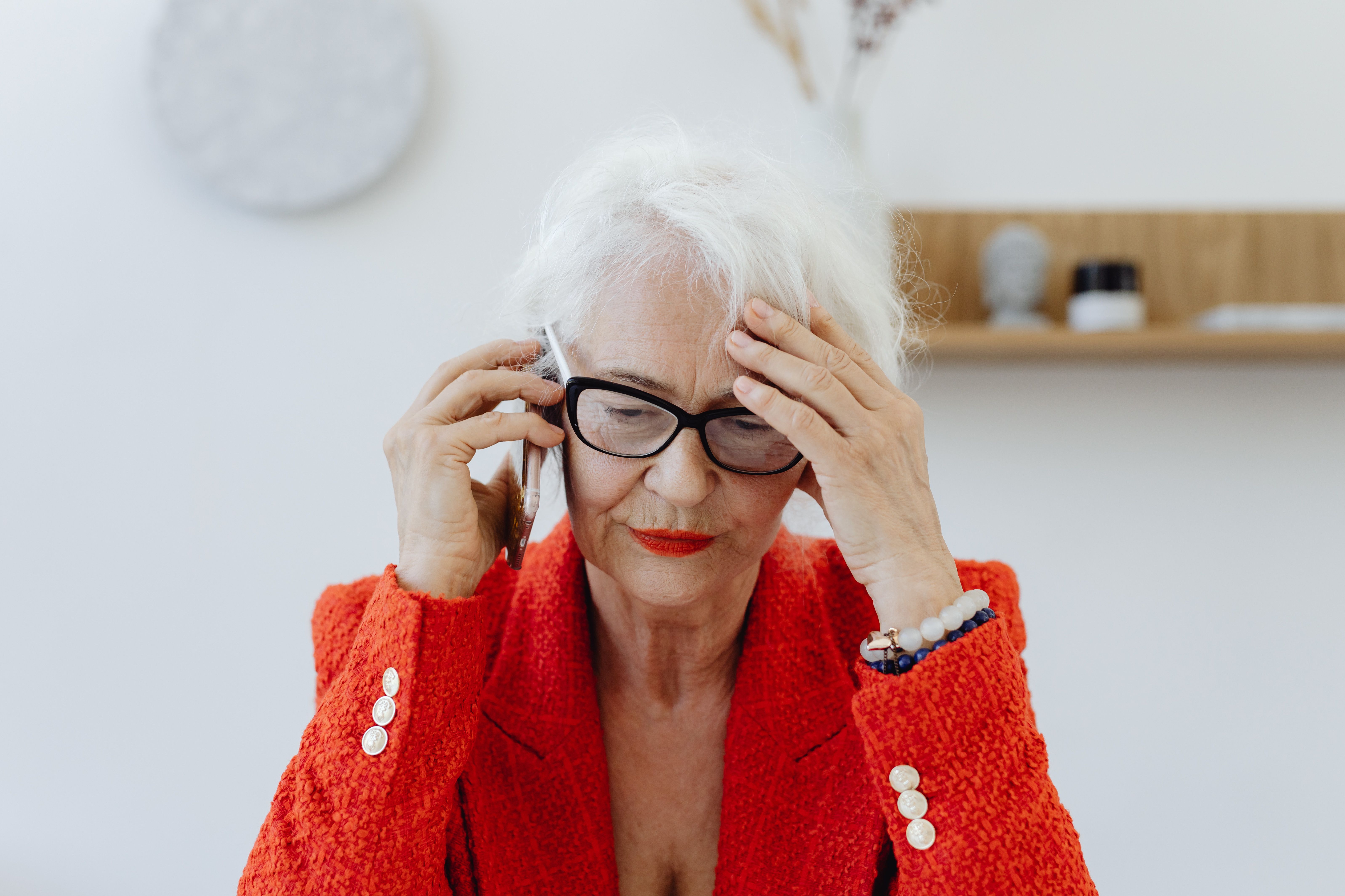 An elderly woman is speaking on the phone.
