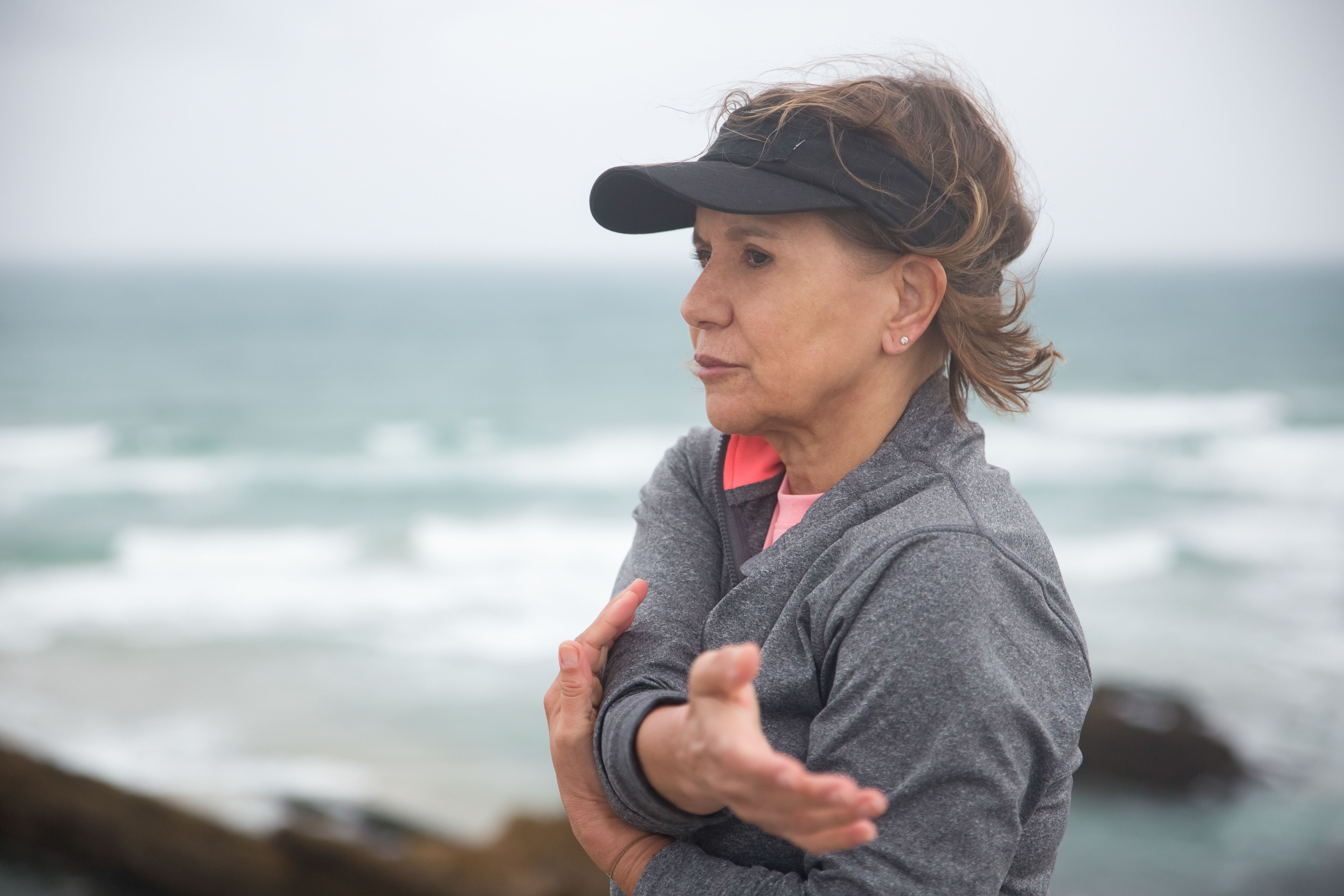 An elderly woman at the beach notices something.