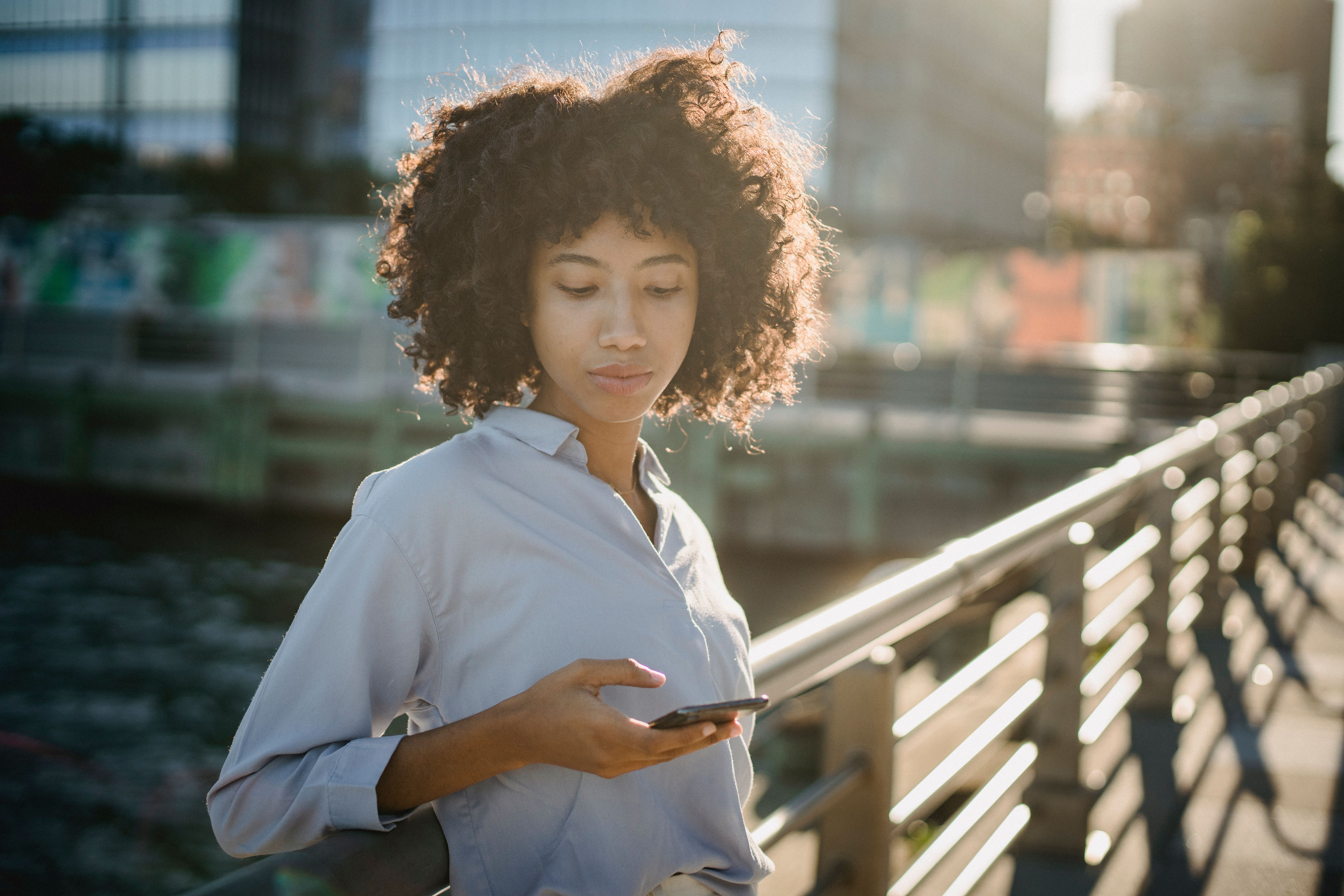 A woman looks seriously at a phone.