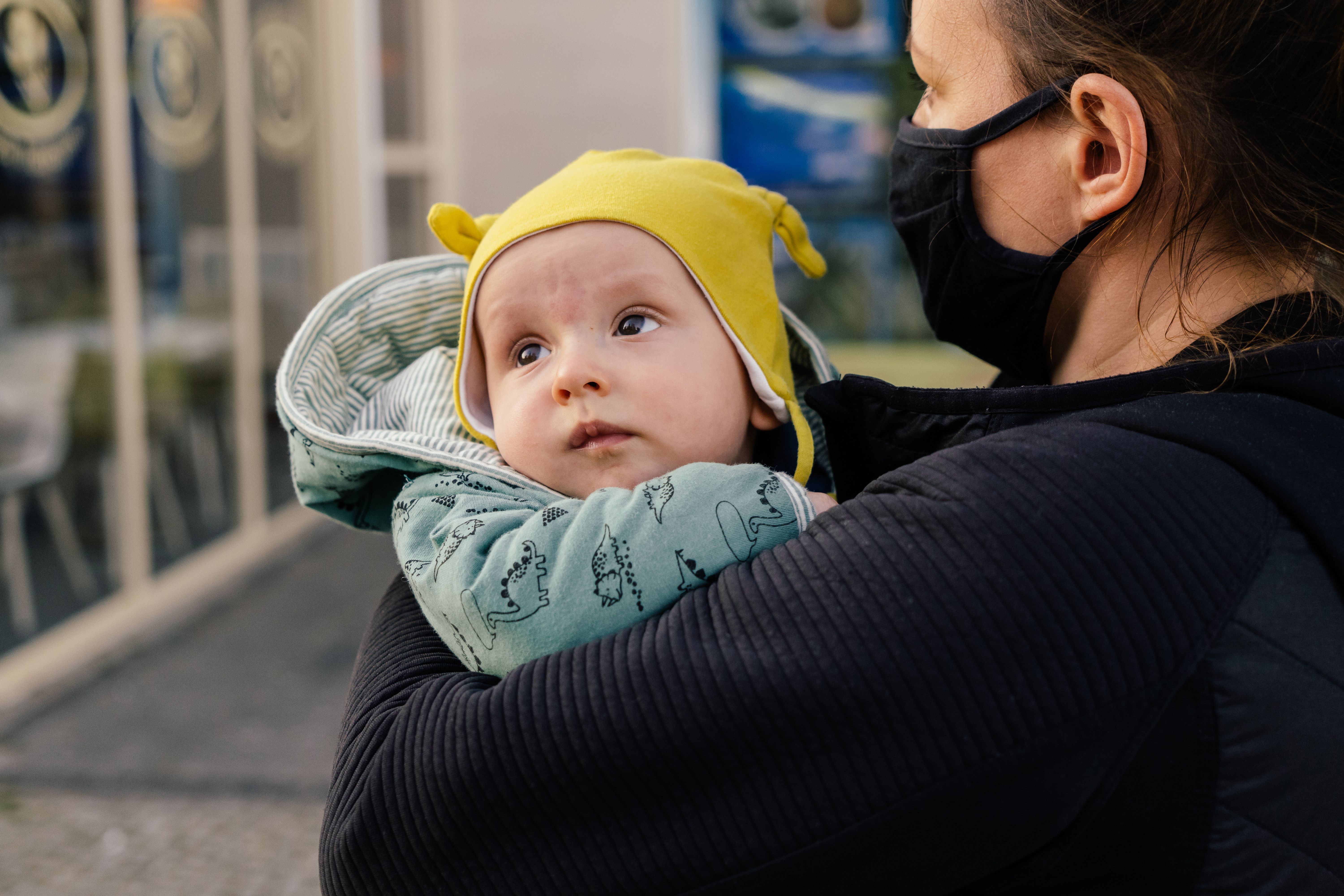 A busy mom is multi-tasking while carrying her baby.