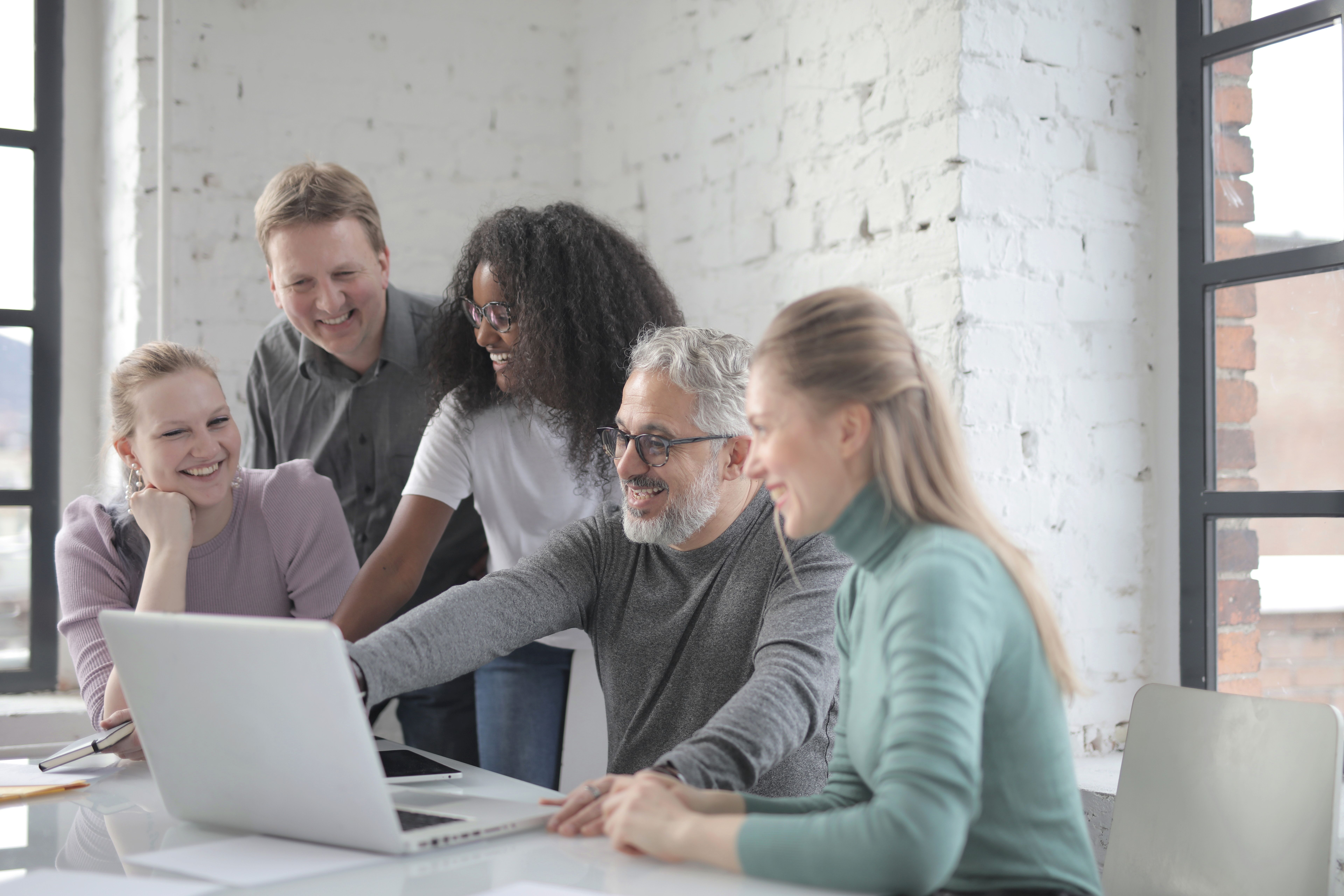 Employees look at something on a laptop and laugh.