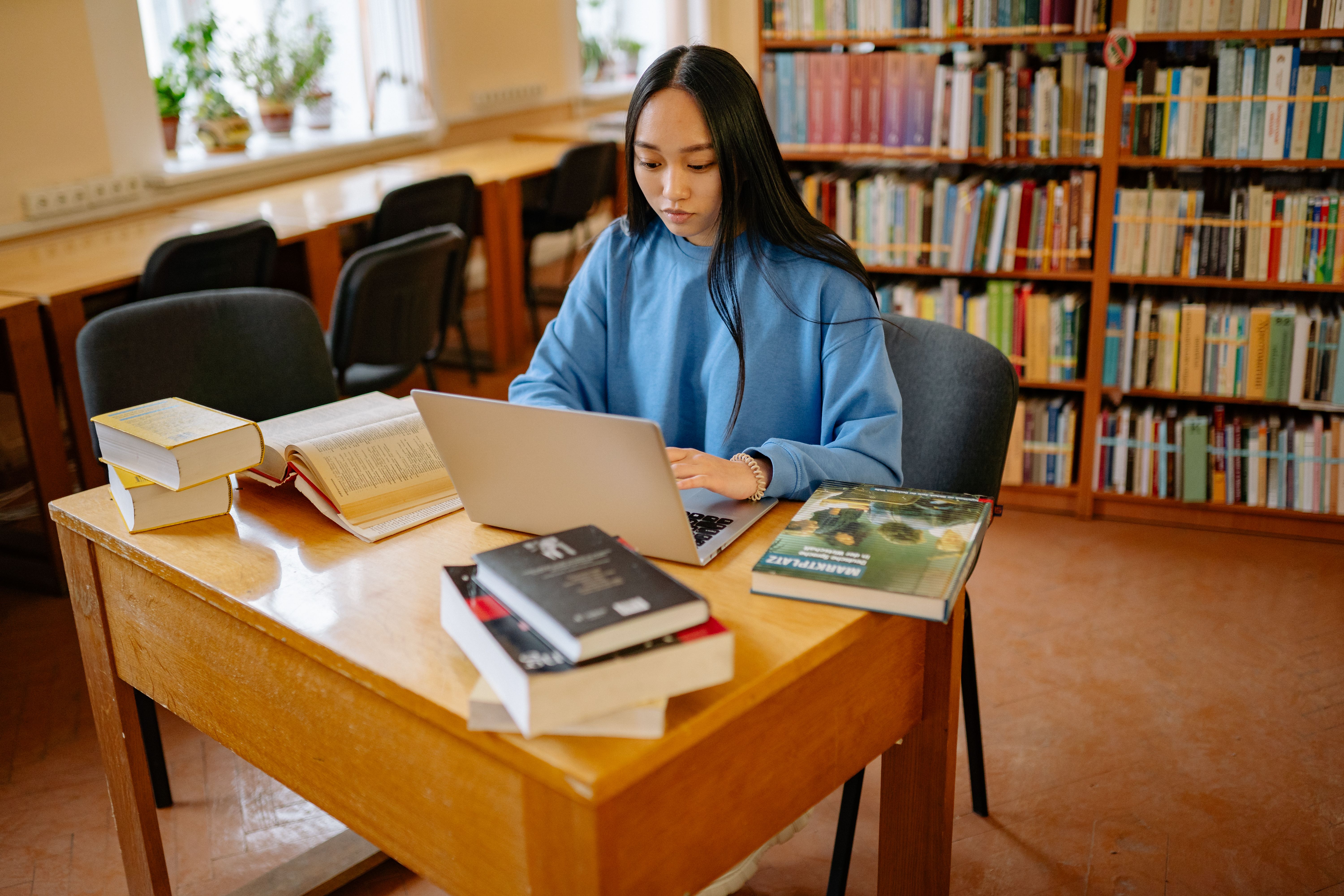 A woman is engrossed in typing something on laptop.