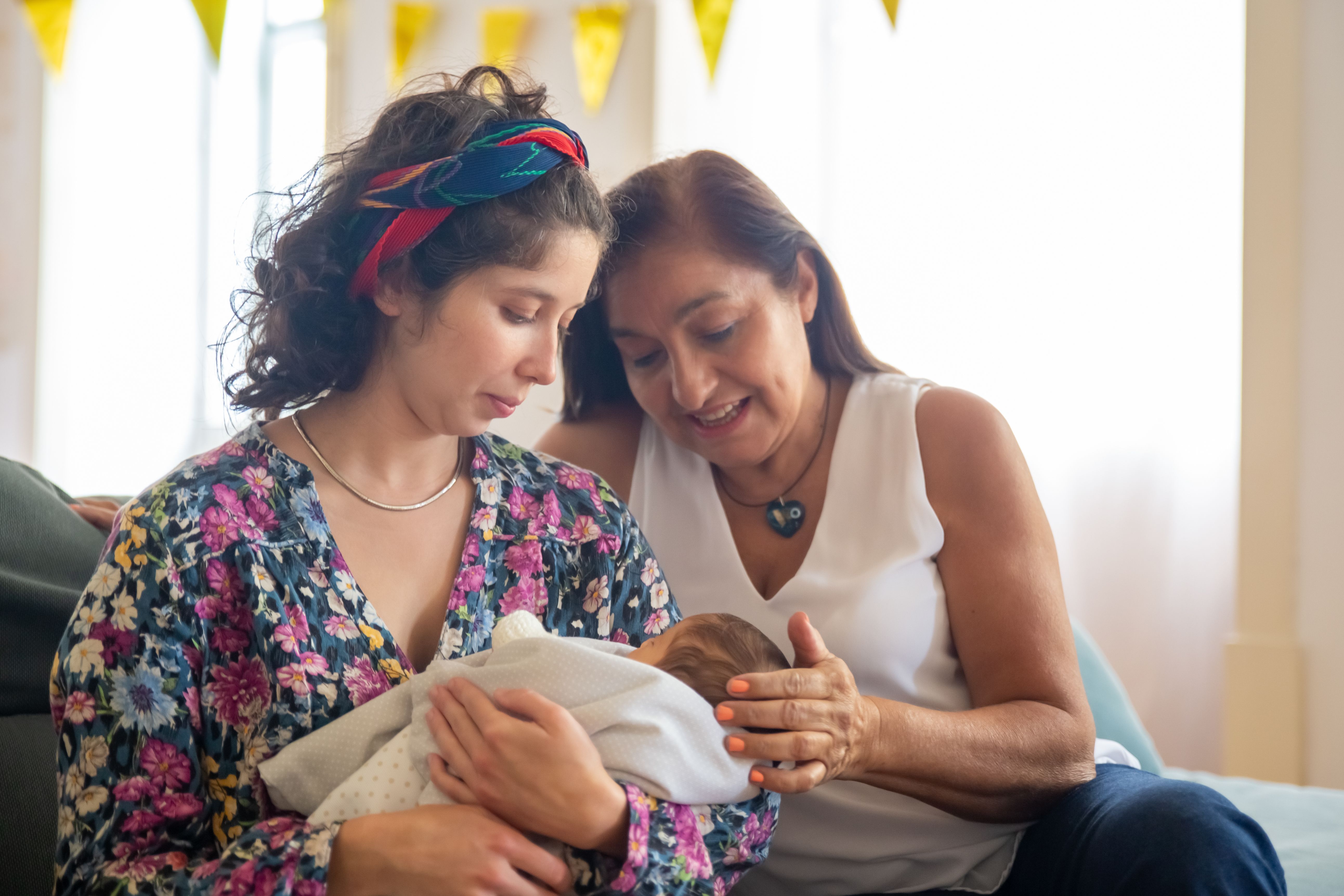 A woman looks at an infant and makes a comment to mom.