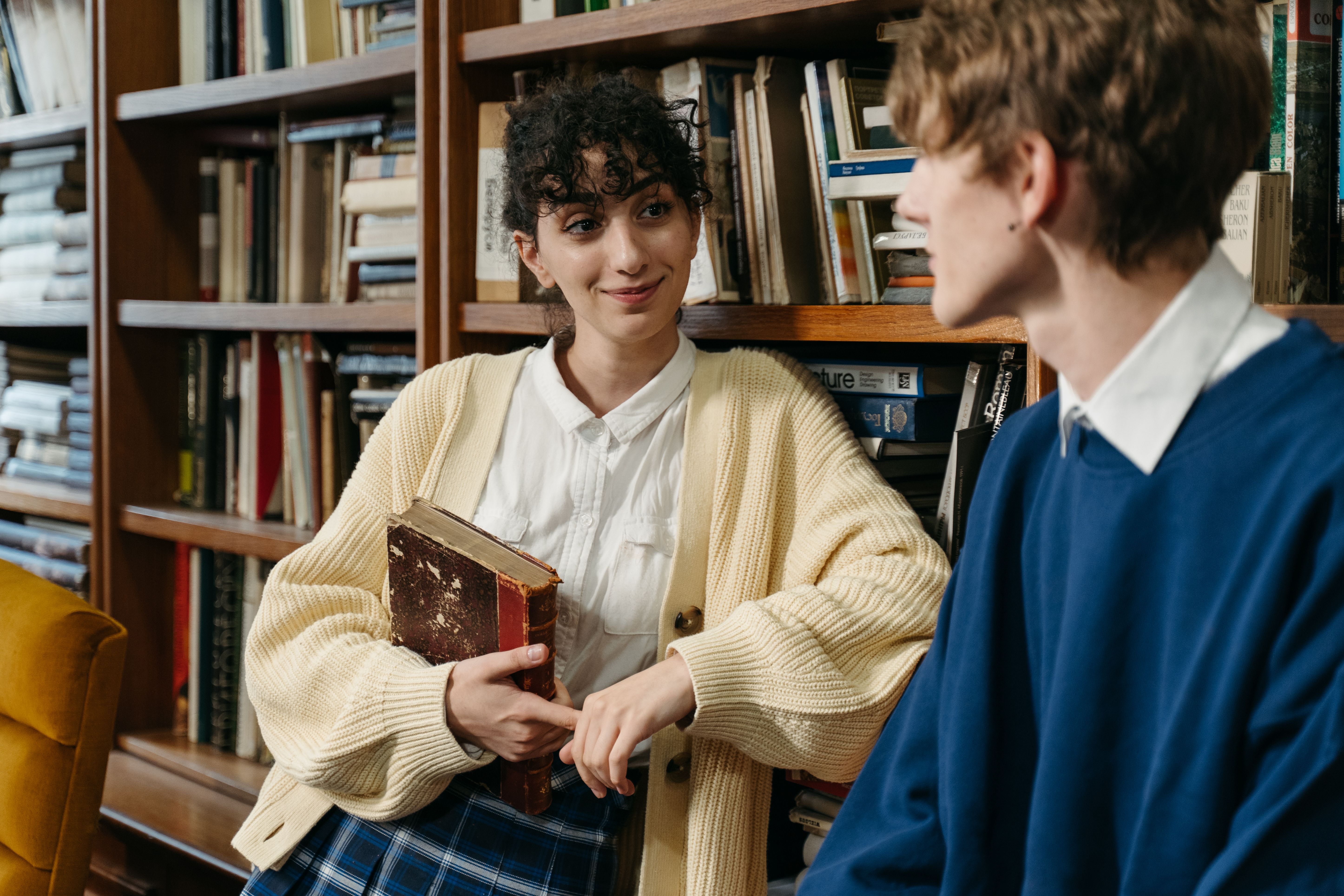 Two people have a cheerful conversation in a library (Representative Image Source: Pexels | Tima Miroshnichenko)
