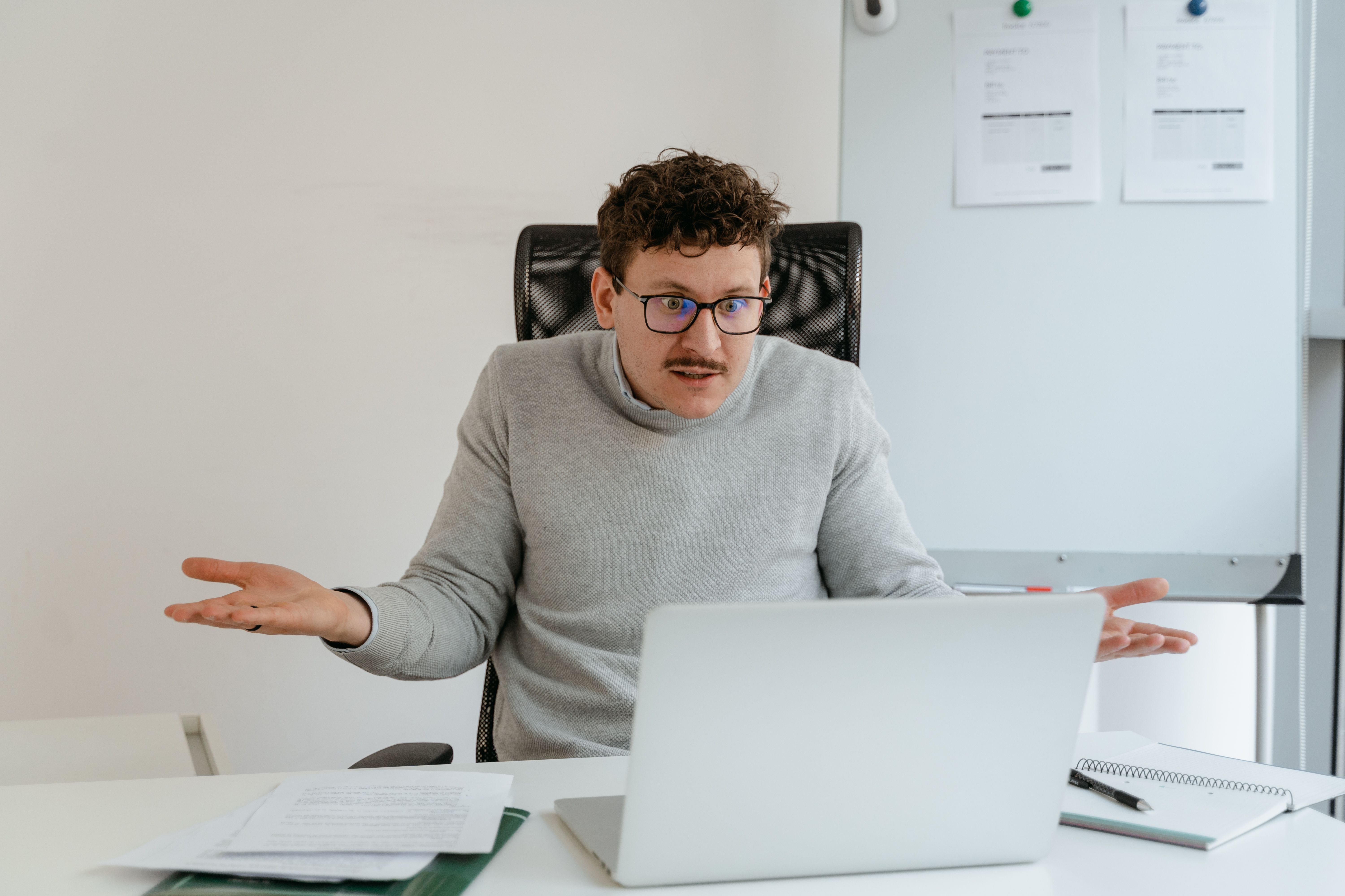 A man in his office looks confused and agitated.