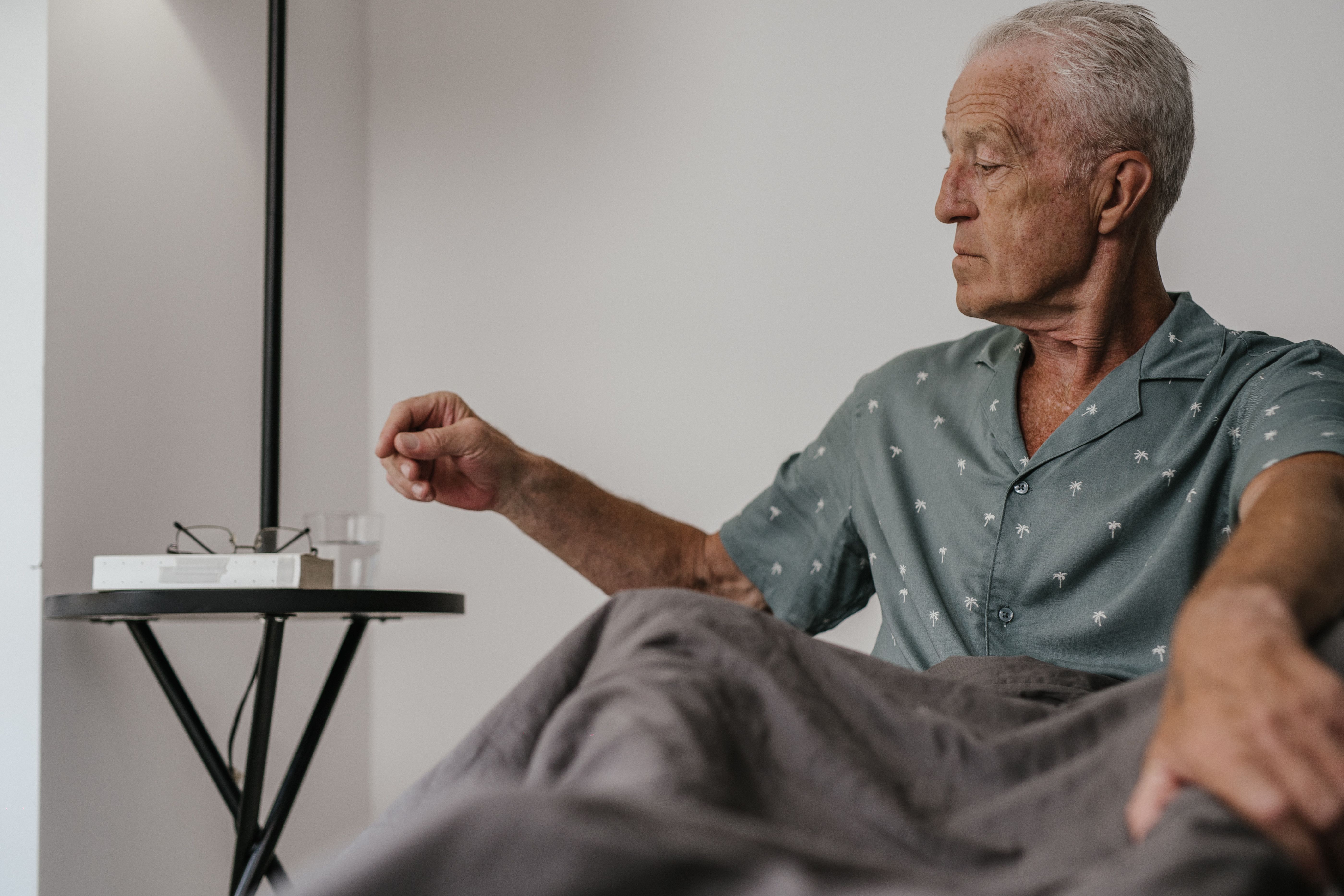An elderly man is taking medication.