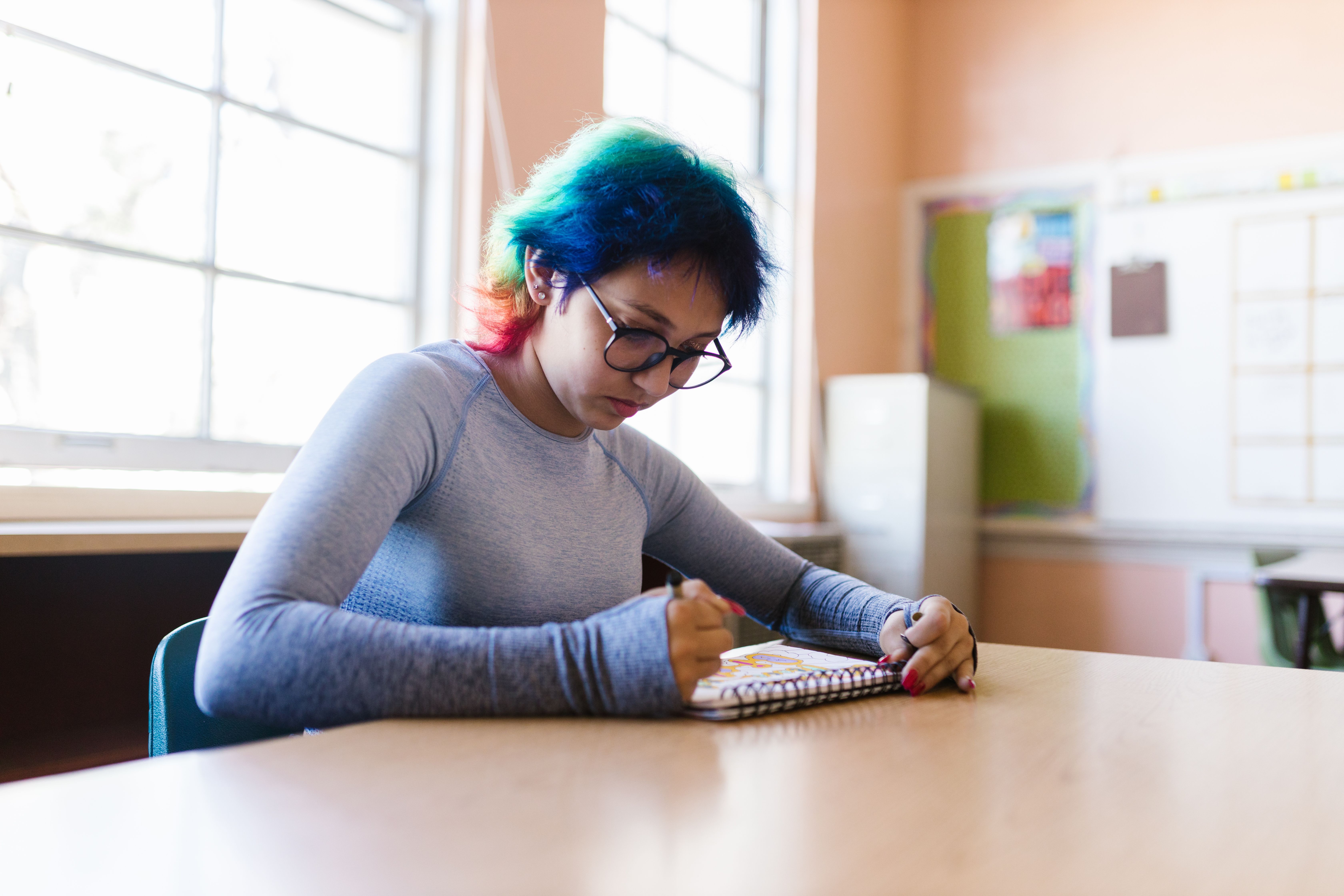 Teenager sits quietly, alone in classroom.
