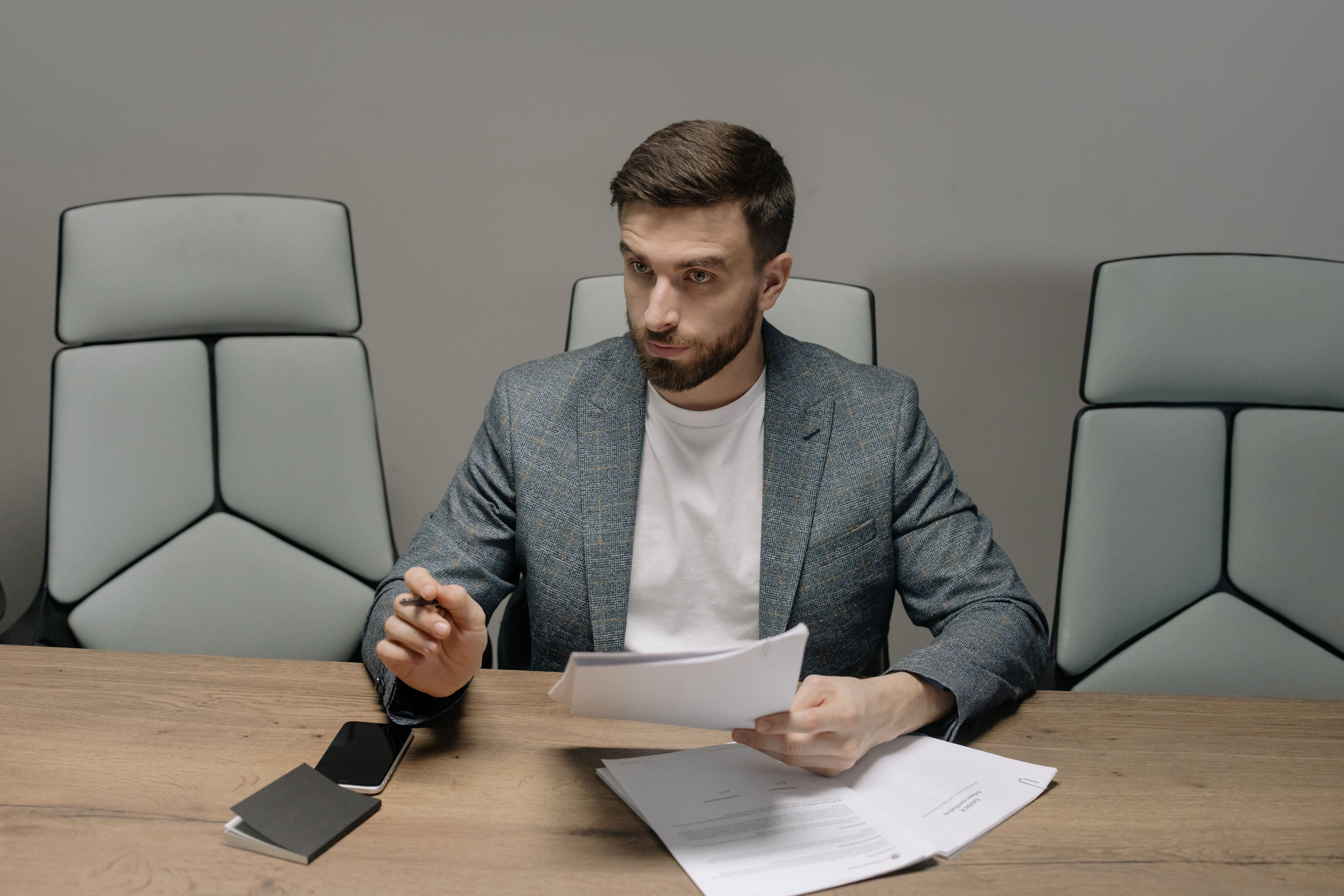 A manager is reading a report and speaking with an employee.