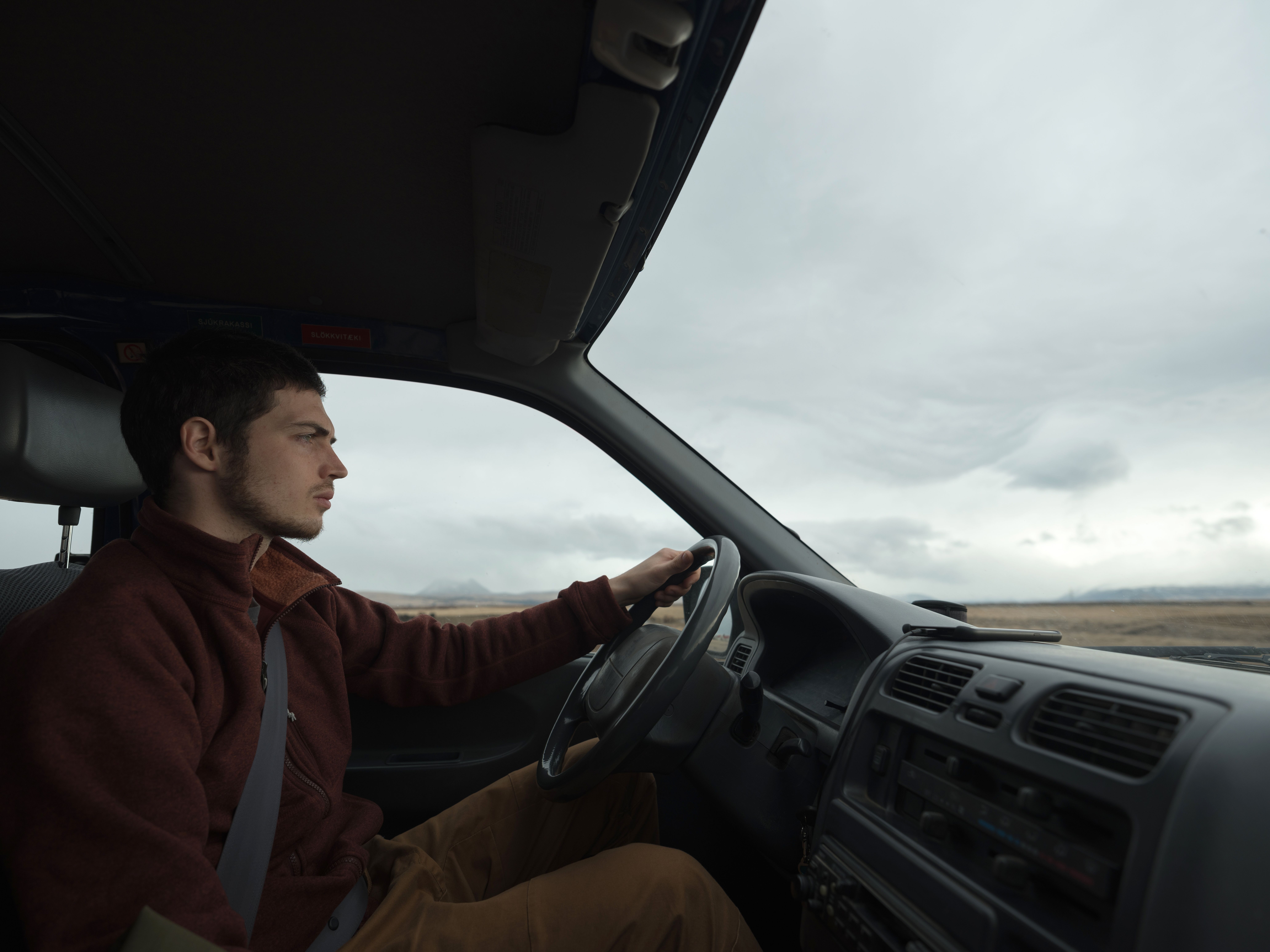 A man looks around suspiciously from his car.