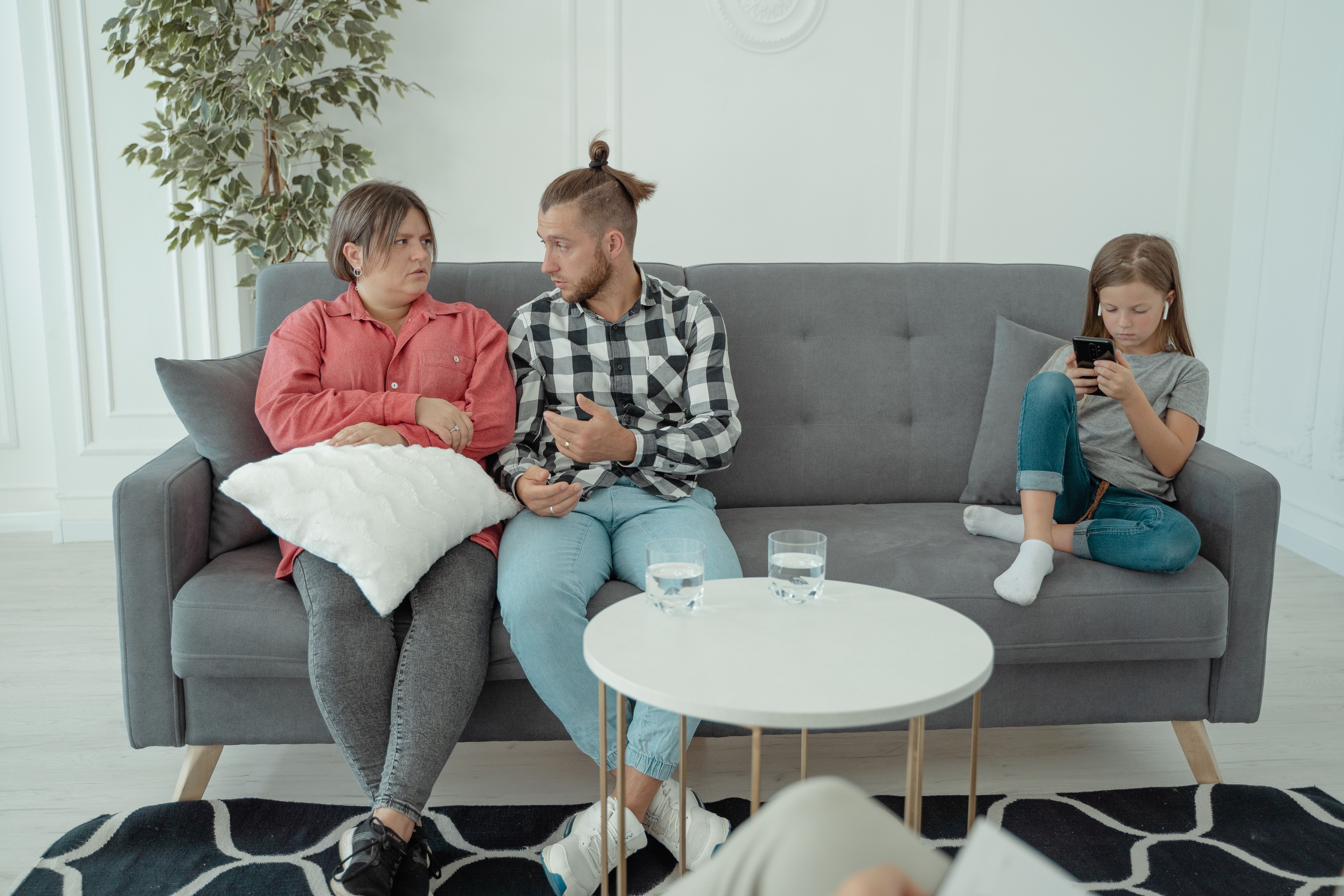 A man is yelling at his wife while the daughter sits beside them.