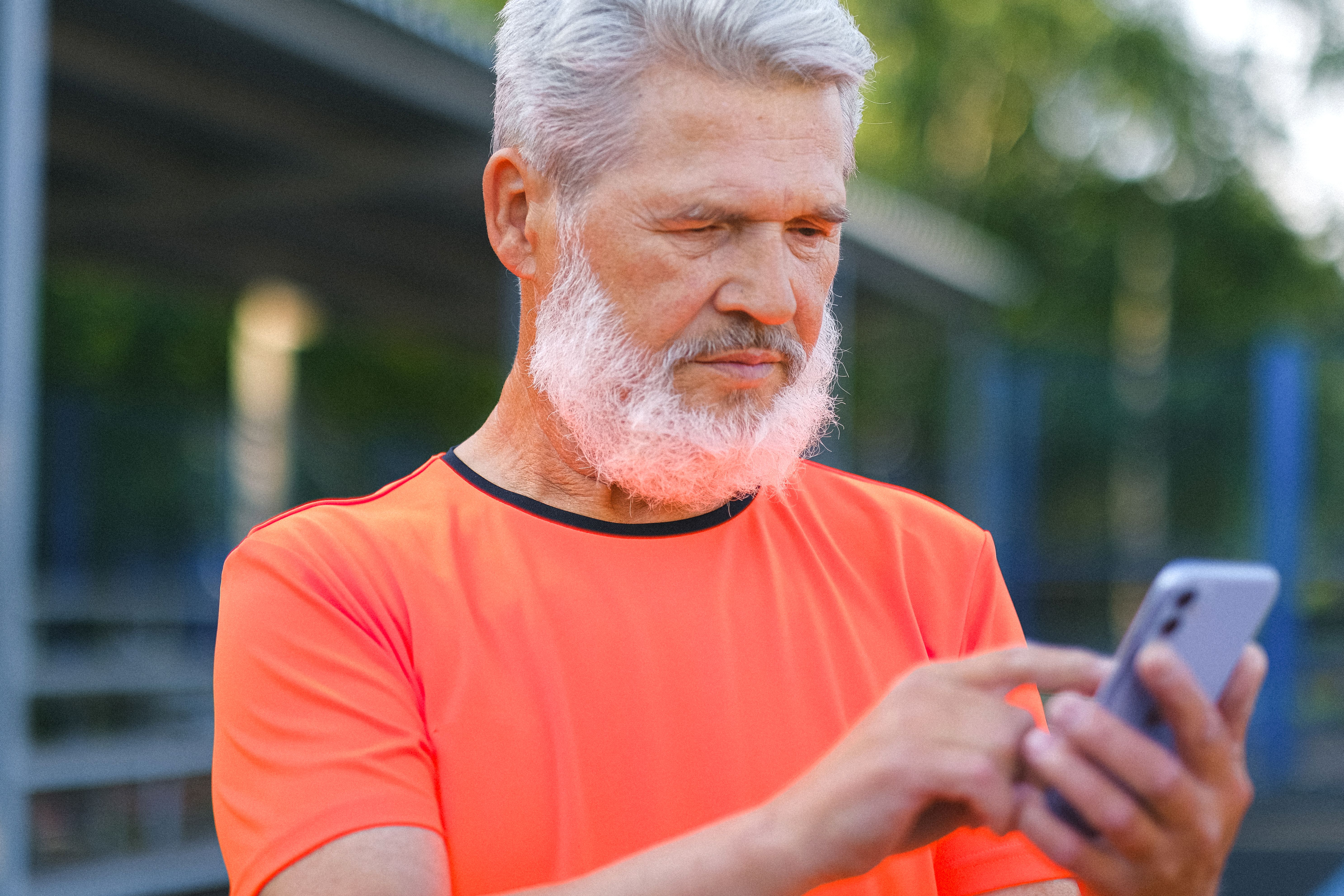 An elderly man looks enraged as he looks at his phone.