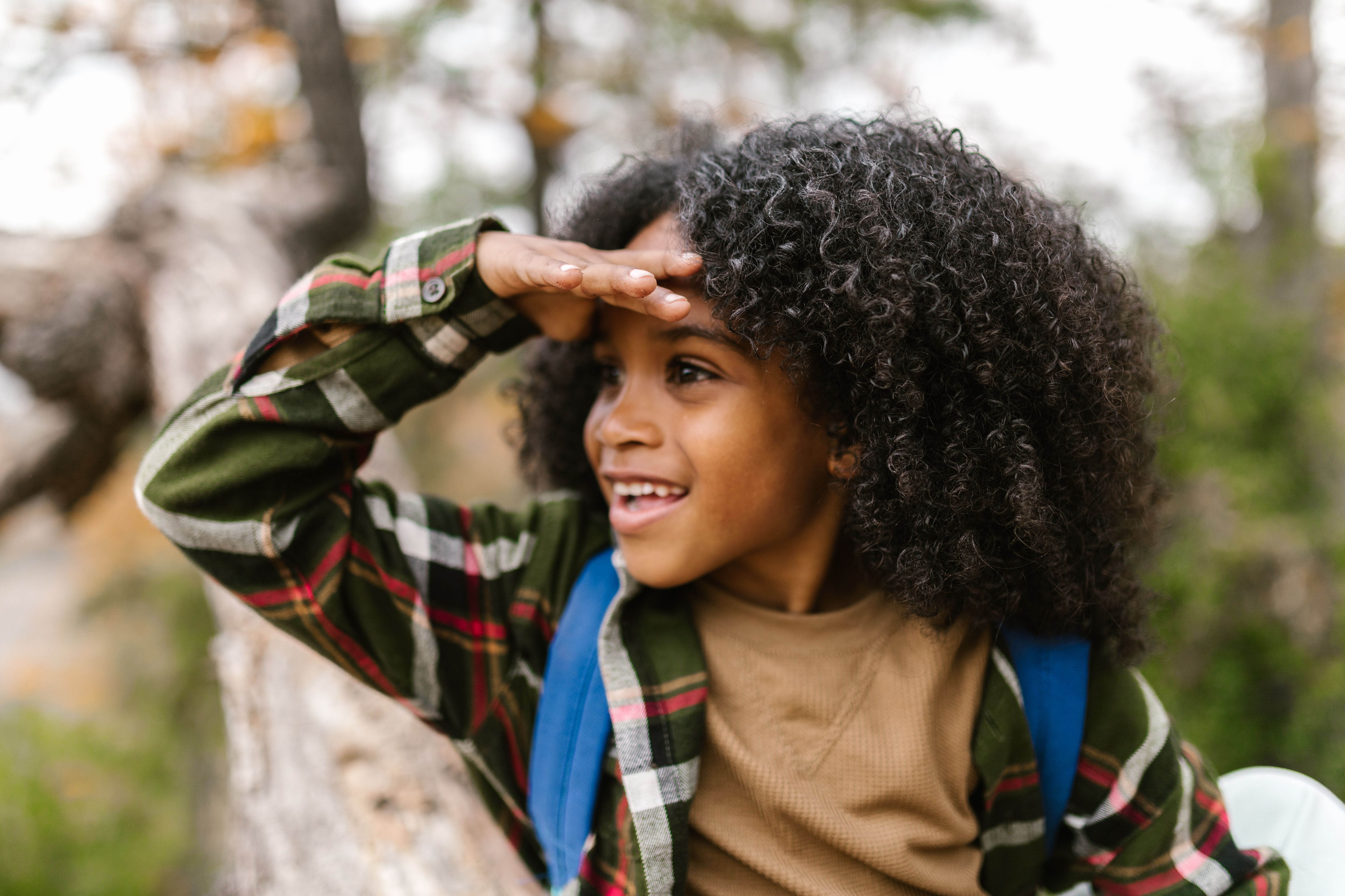 A little boy with long, curly hair smiles.
