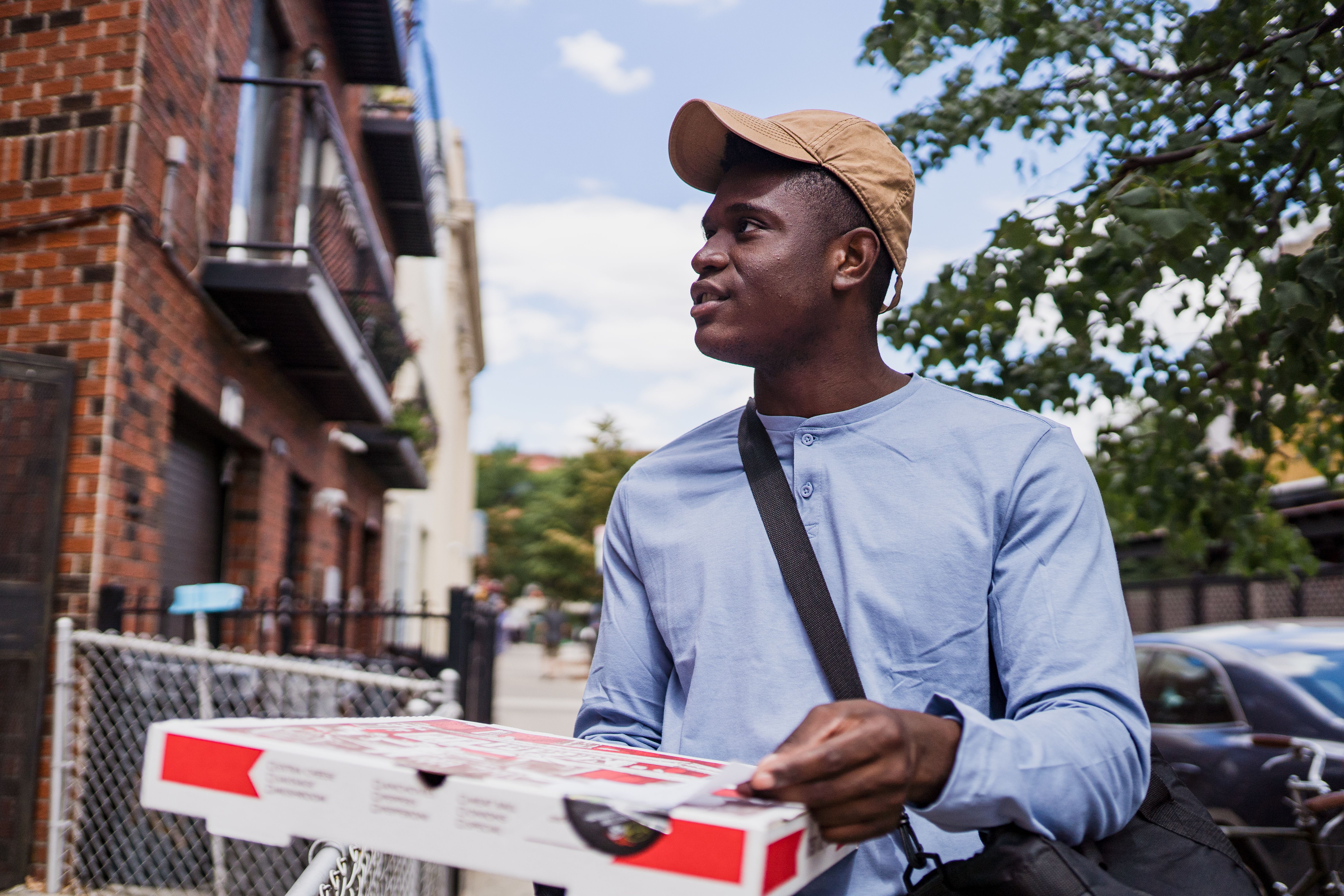 A deliver driver holding a pizza box.
