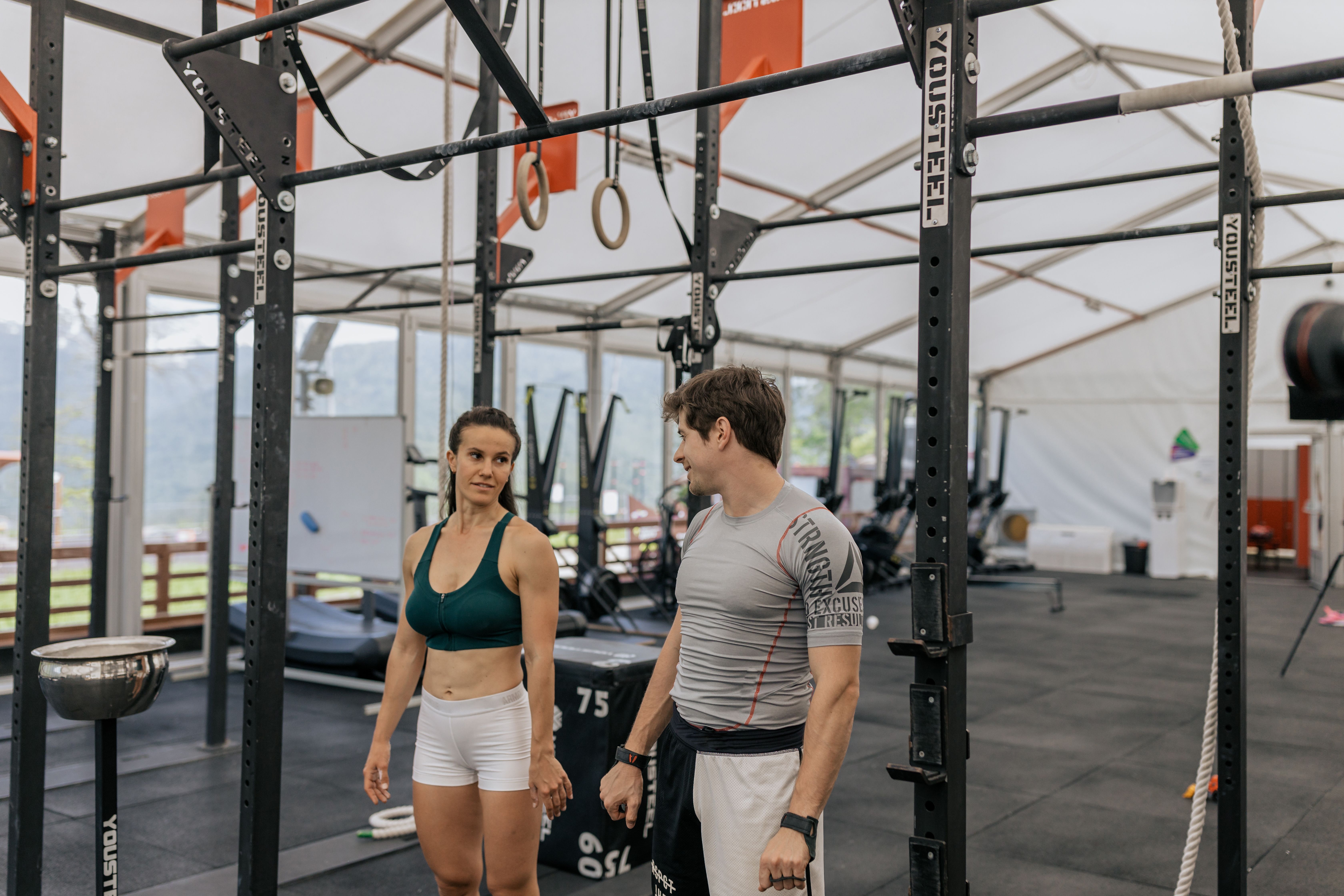 A man is speaking with a woman at the gym.