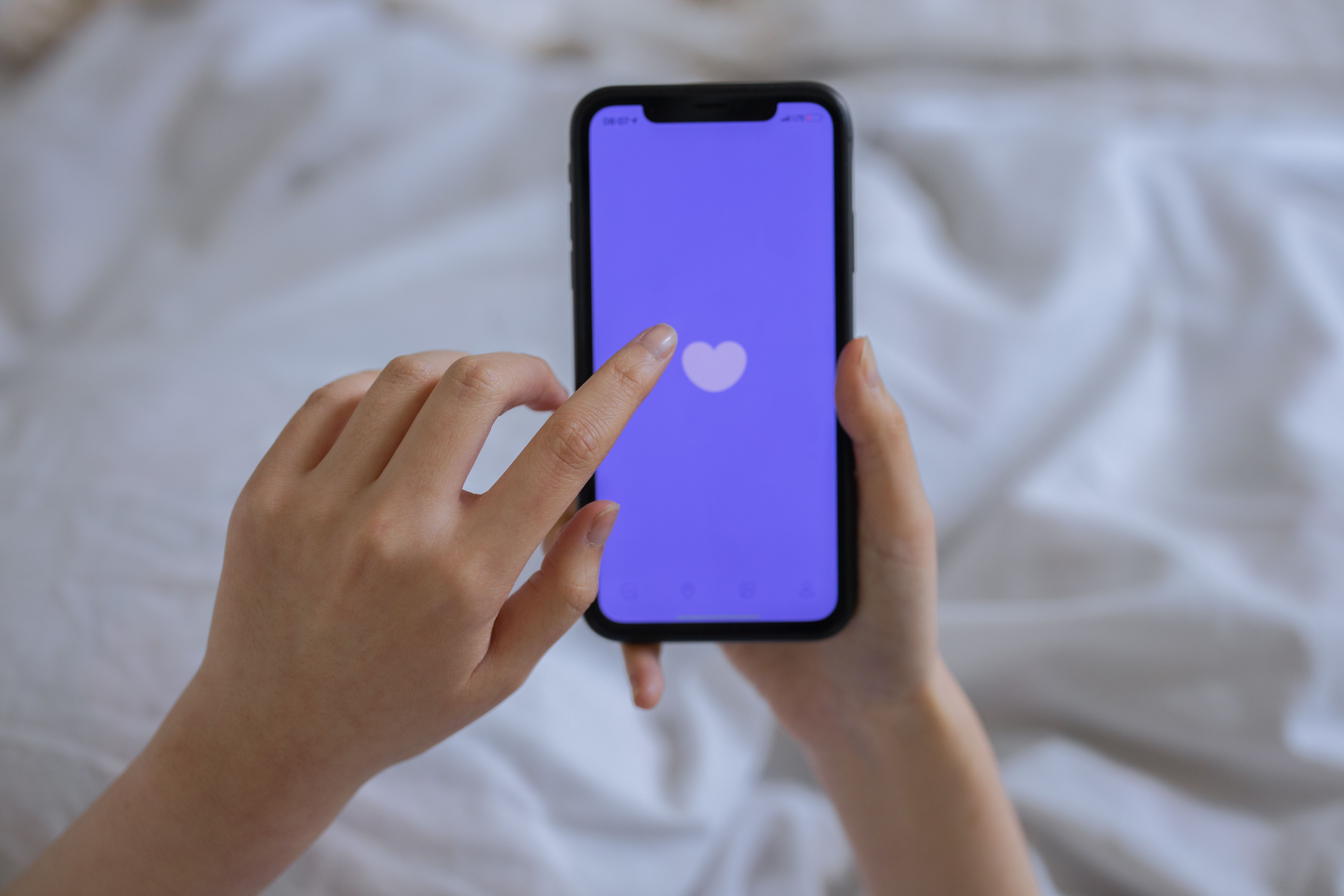 A person is opening a dating app on their phone.