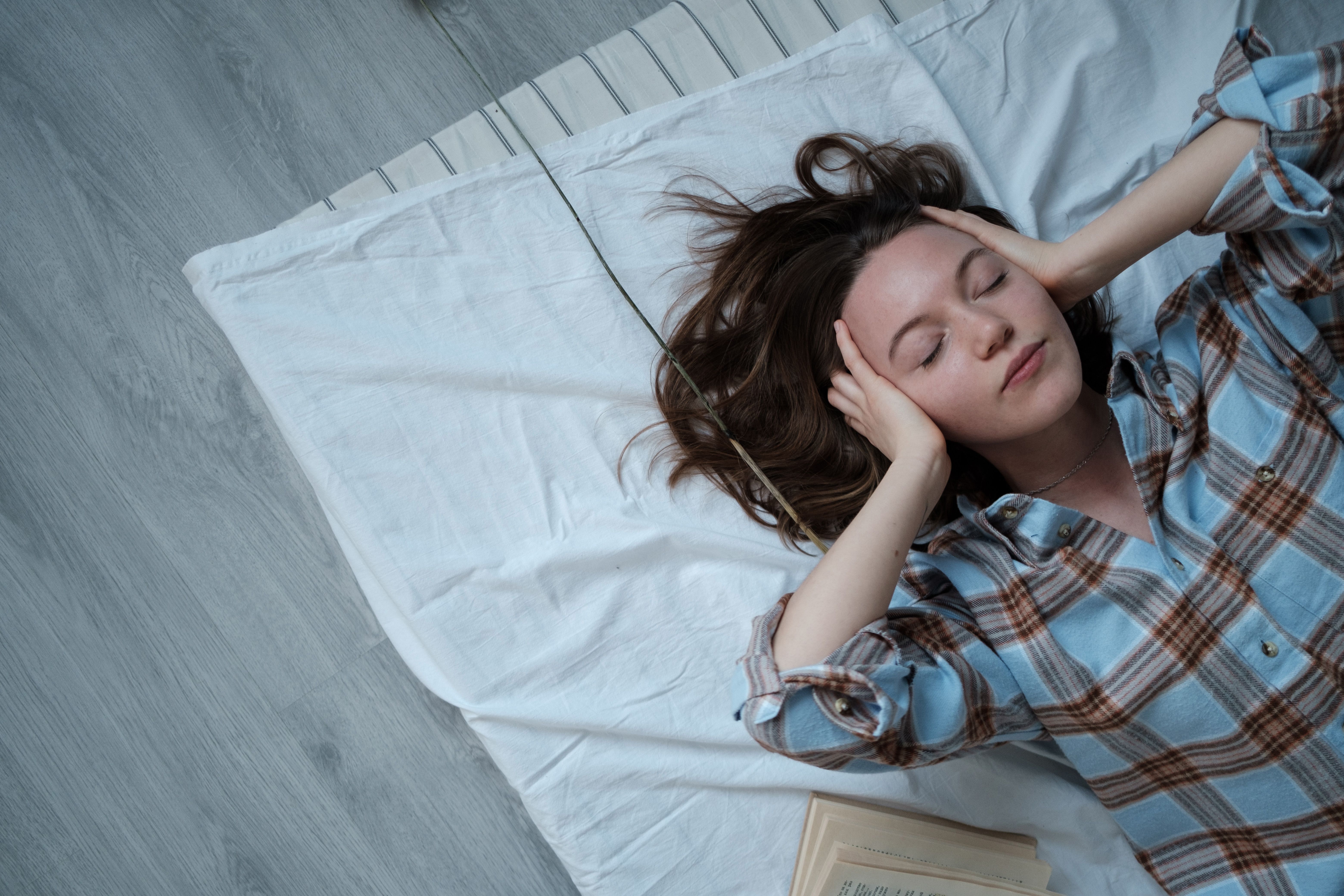 A frustrated woman covers her ears due to overbearing noise.