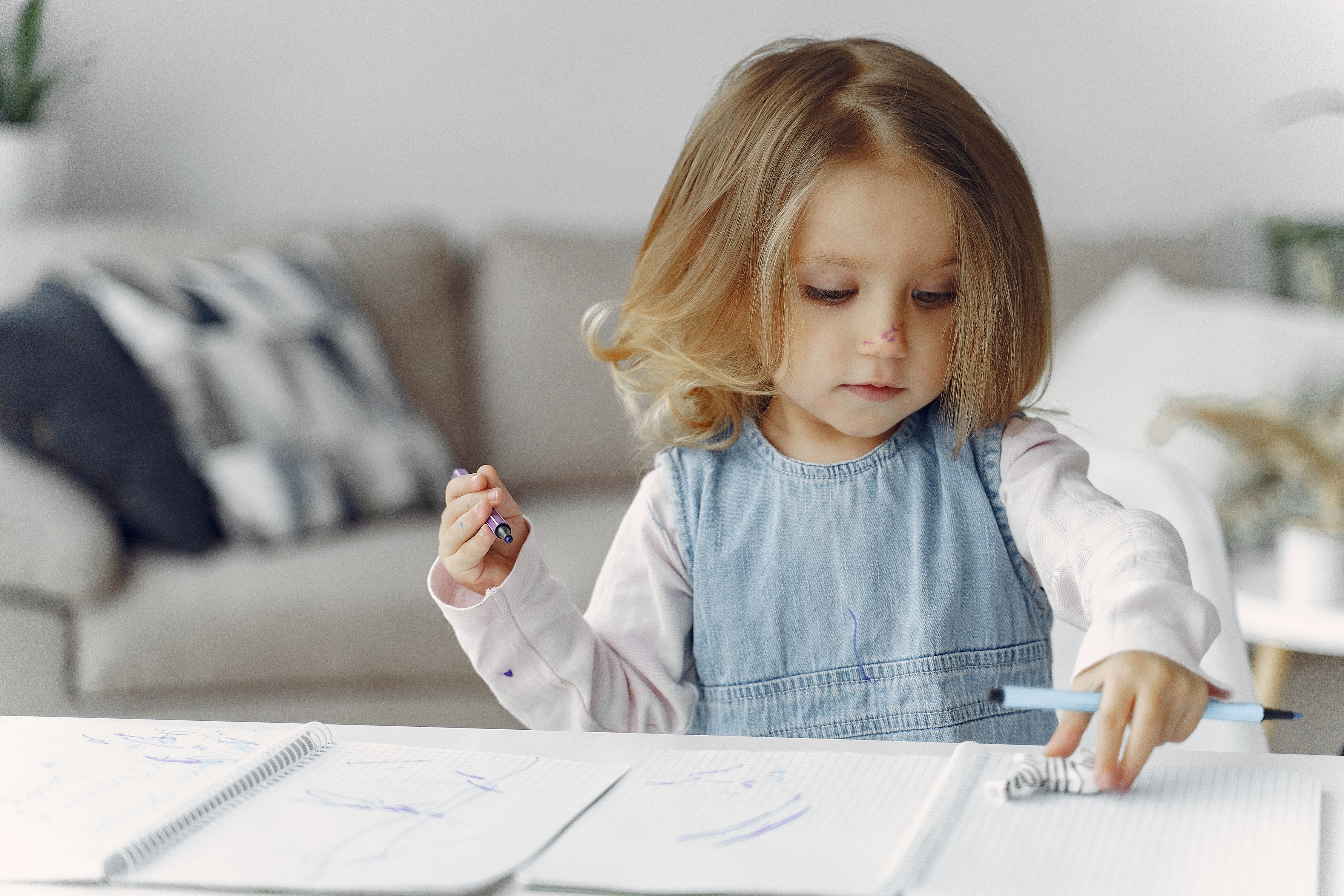 A little girl is playing with crayons and markers.