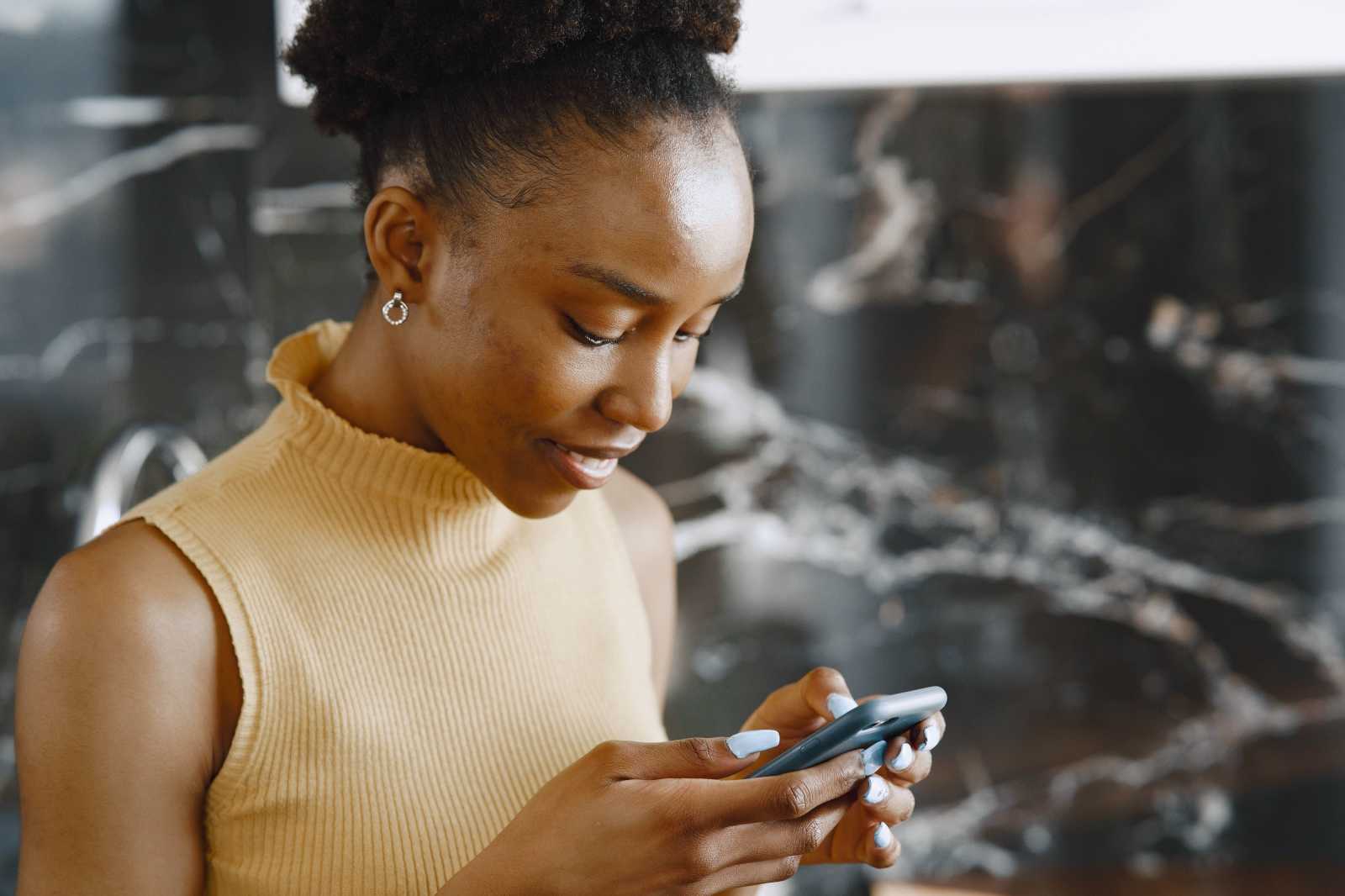 A woman looks at her phone disappointed.