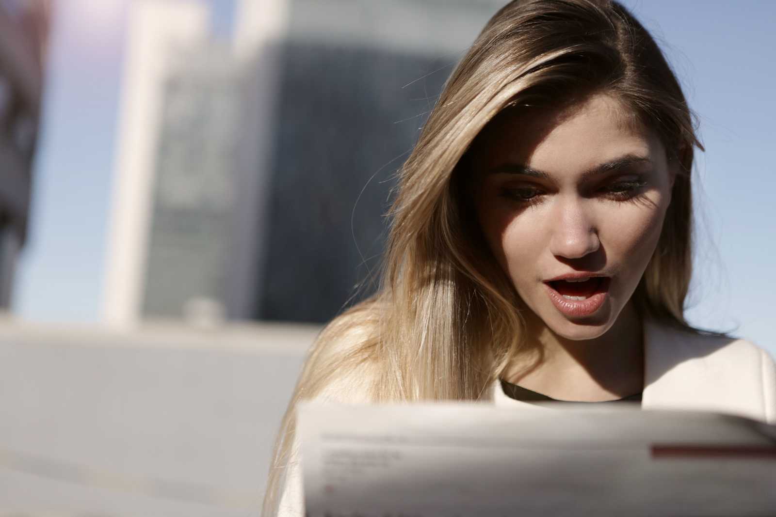 A woman reading a report, looking shocked.