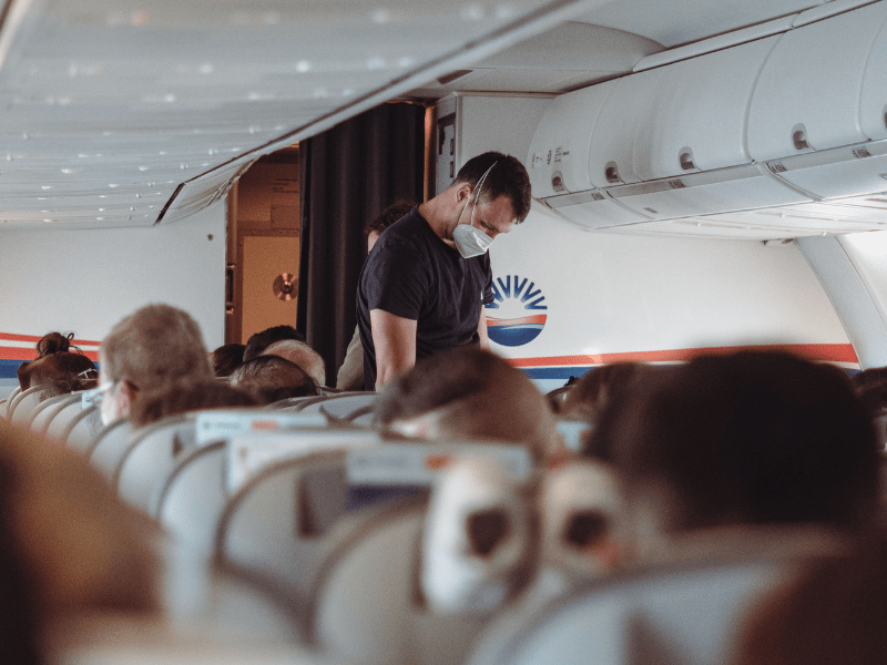 A man makes his way down the aisle of an airplane while other passengers remain seated. (Representative Image Source: Pexels | Hasan Gulec)