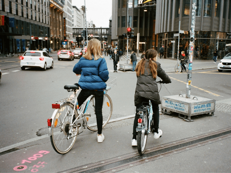 Girls riding bicycles on a busy road.