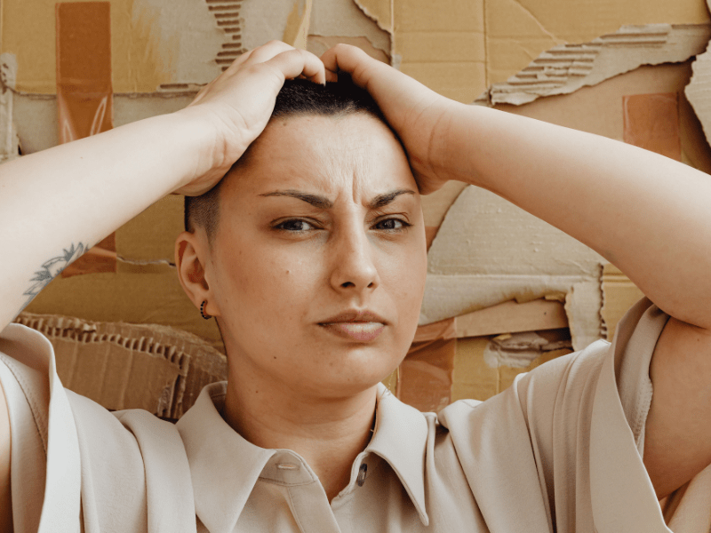 A woman holding her head looking annoyed.