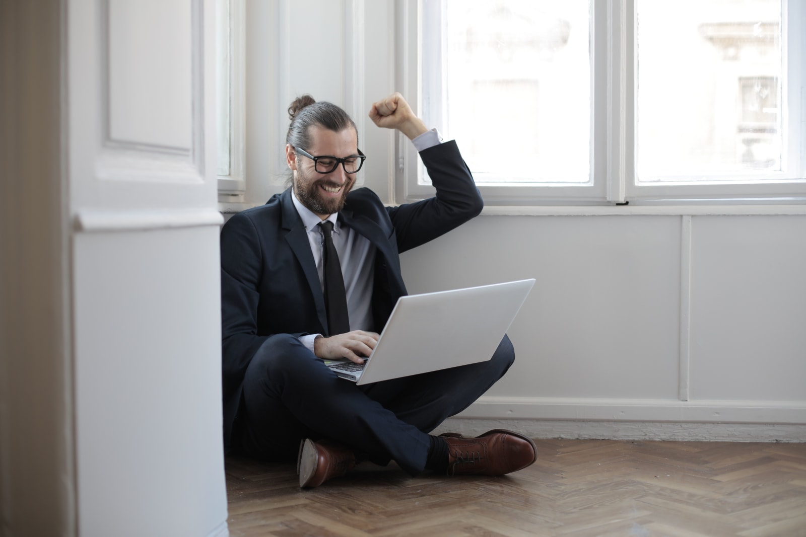 A man celebrating while looking at his laptop.