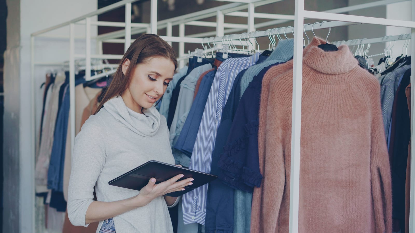 Shop assistant using tablet to manage clothing inventory in a fashion boutique. (Representative Image Source: Pexels | Vitaly Gariev)