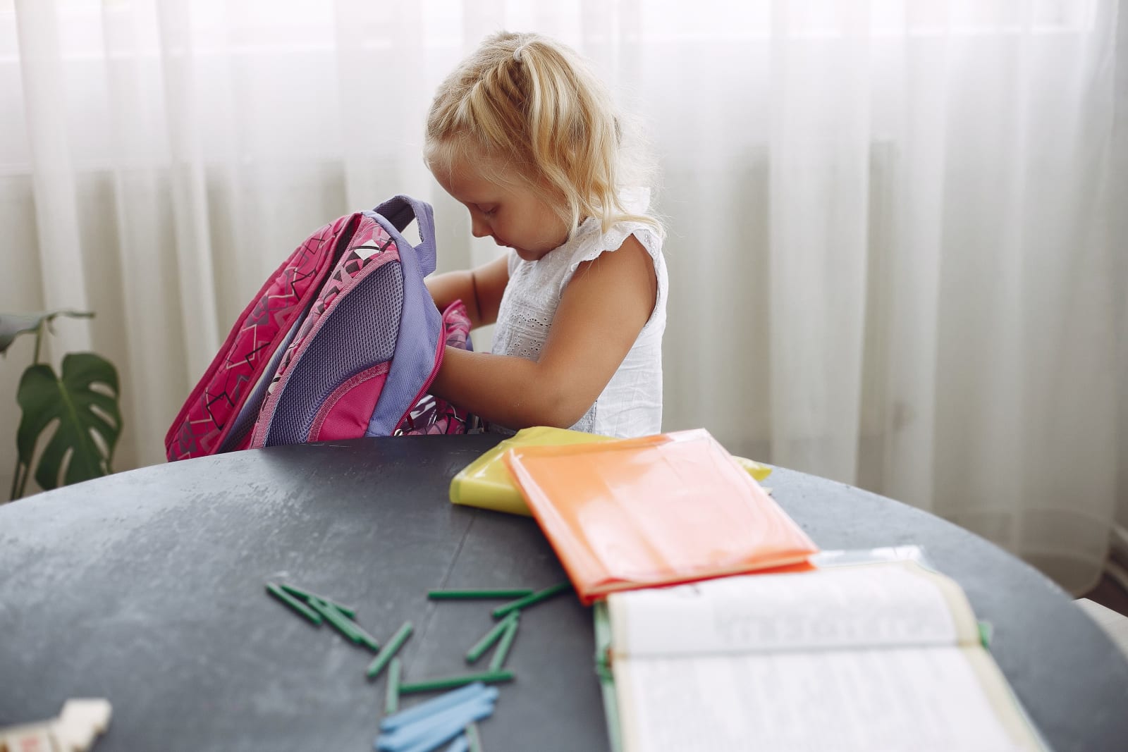 A little girl is packing her backpack.