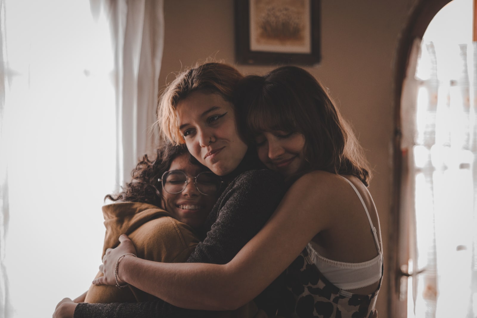 Three friends affectionately hug each other.