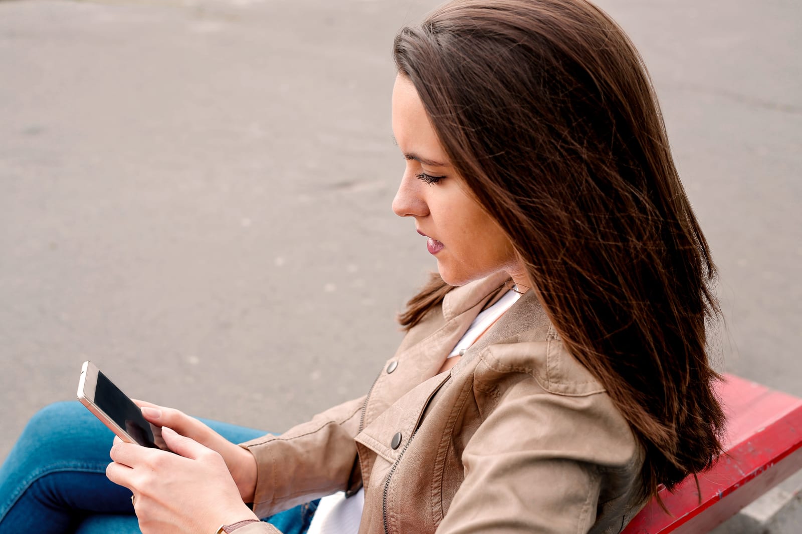 A woman looks disappointed while checking her phone.