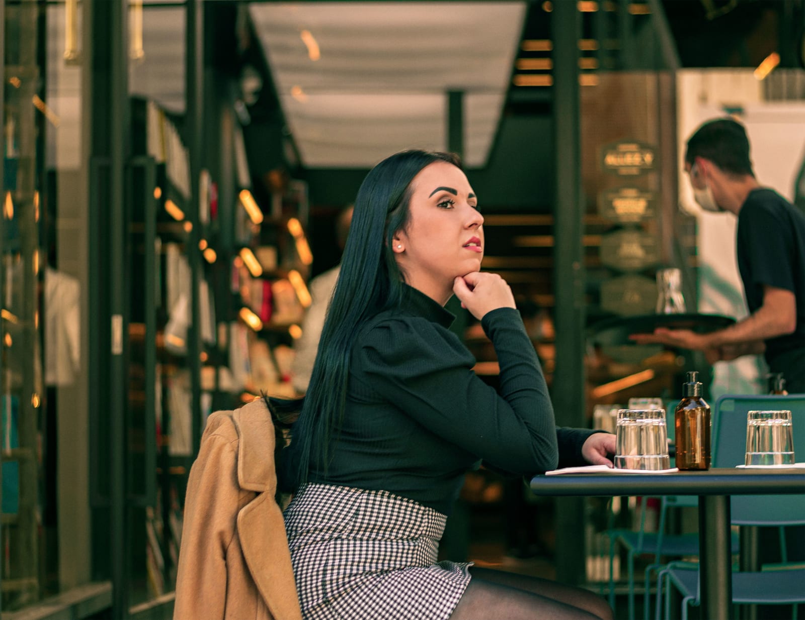 A woman at a restaurant watching someone disappointedly.