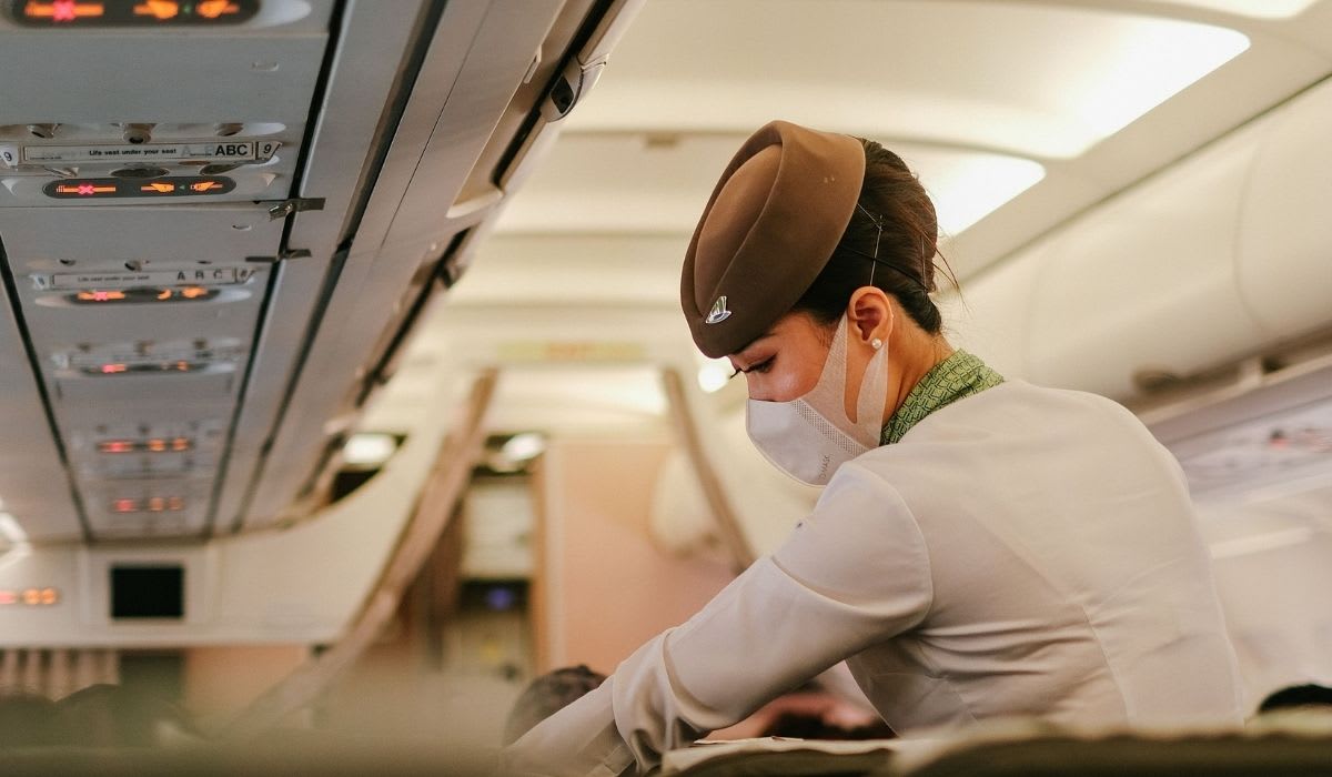 A flight attendant performs duties onboard a passenger airplane while wearing a protective mask. (Representative Image Source: Pexels | Pew Nguyen)