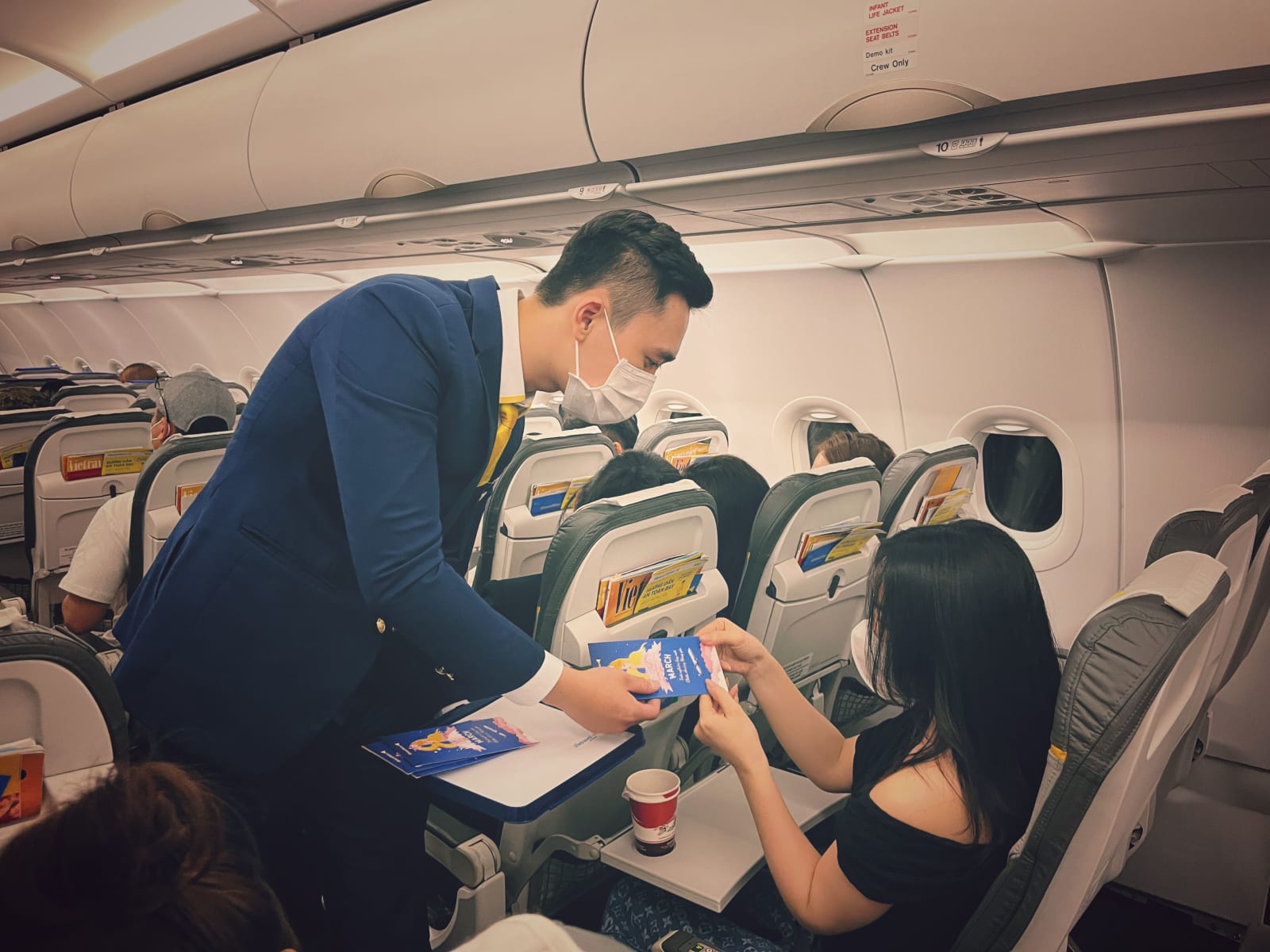 A male flight attendant speaking with a passenger.
