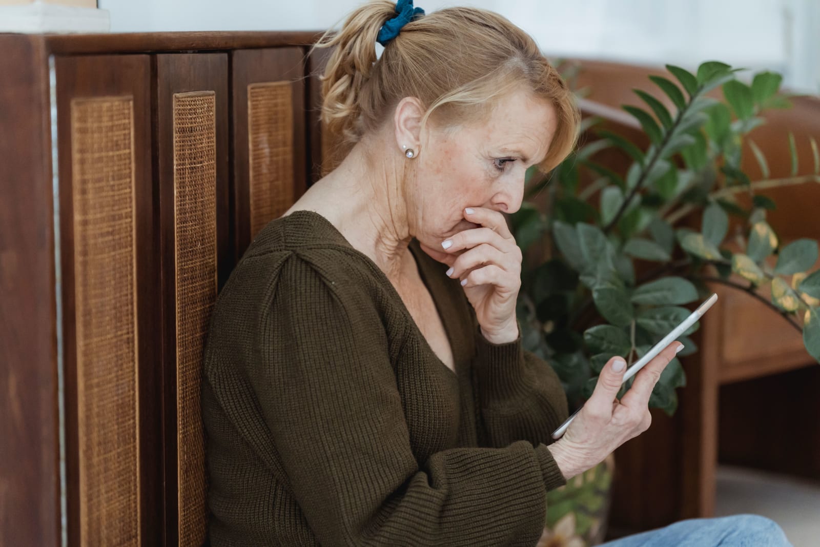 A woman looks at her phone in disbelief.