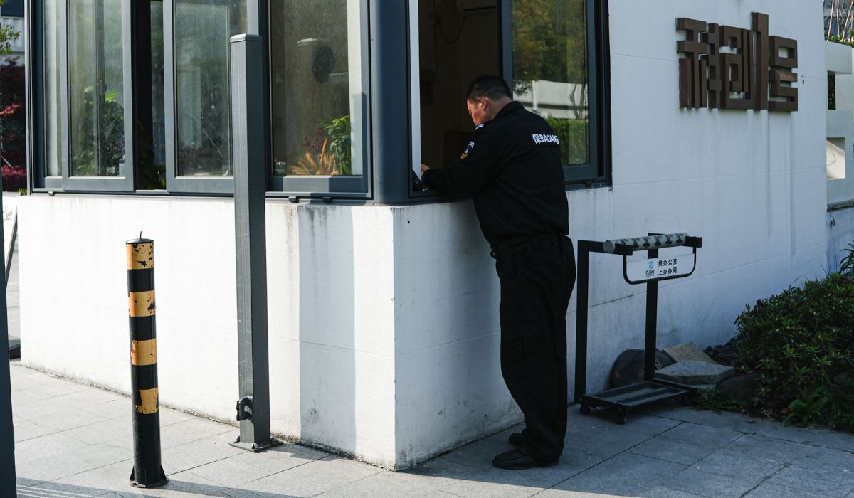 A security guard stands at a modern entrance of a building during the daytime. (Representative Image Source: Pexels | 女子 正真)