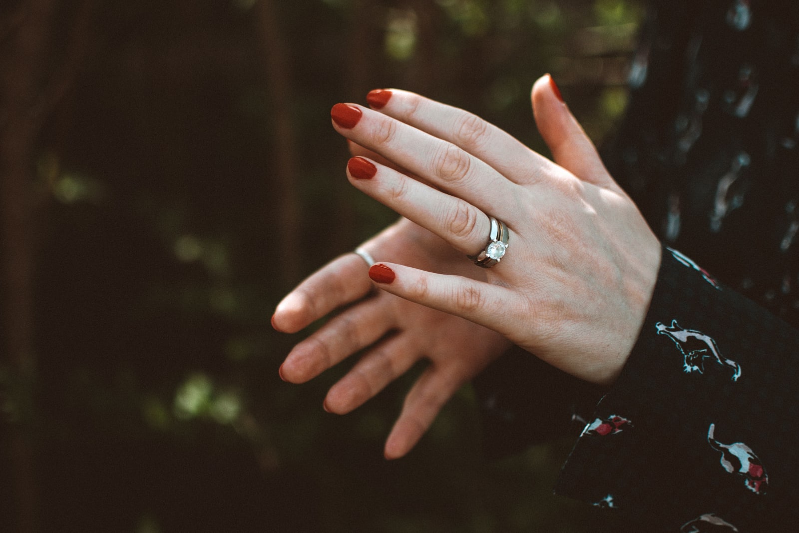 Close-up of hands with red nails showcasing a diamond ring (Representative Image Source: Pexels | Lisa Fotios)