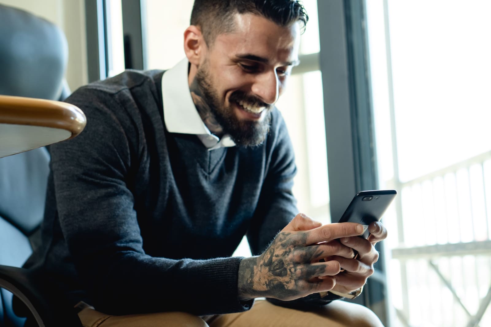 A man looks at his phone and laughs.