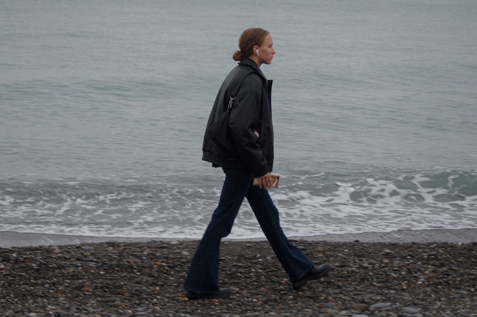 A woman is walking along the shore.