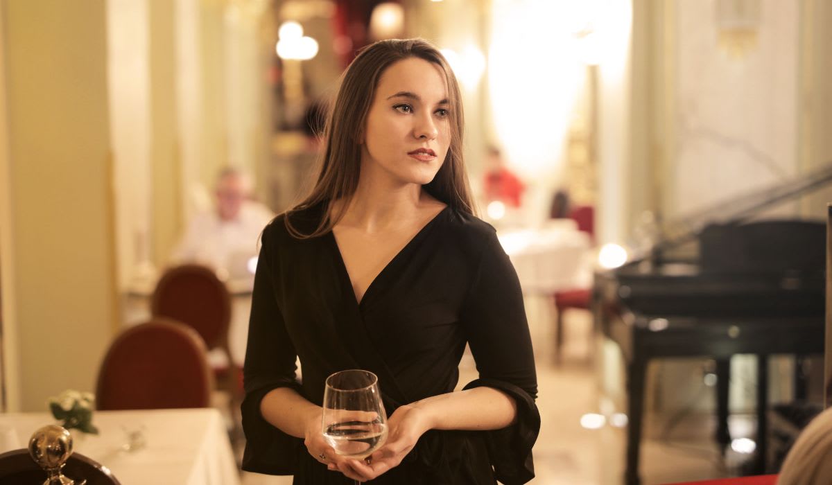 A woman in an elegant black dress looking at someone seated across from her. (Representative Image Source: Pexels | Andrea Piacquadio)