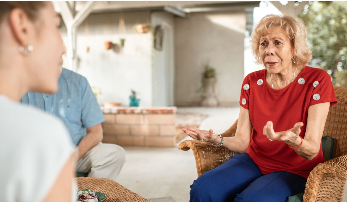 Senior woman in a red shirt chatting expressively with another woman. (Representative Image Source: Pexels |  RDNE Stock project)