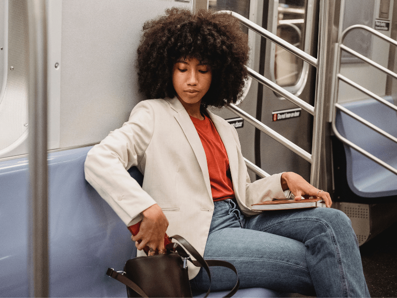 A woman sitting on a train, looking through her bag.