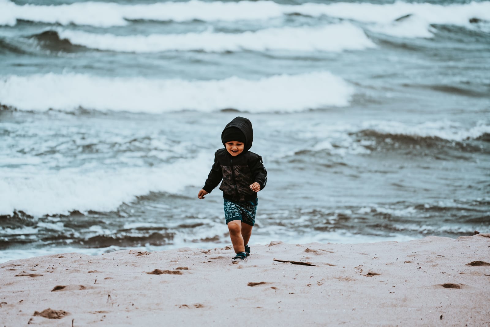 A little boy playing alone by shoreline.