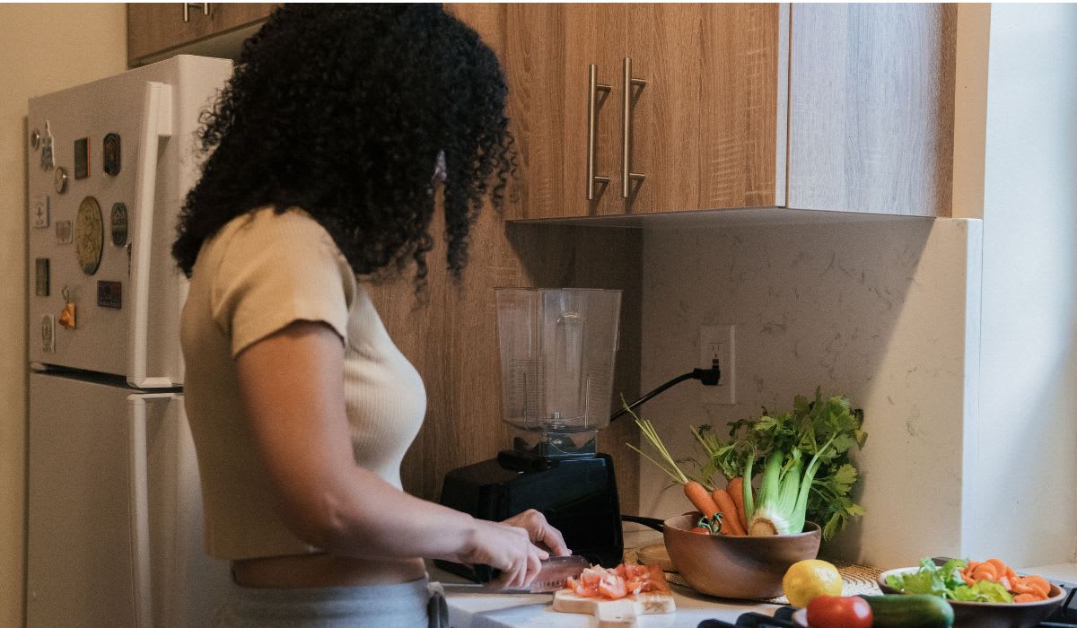 A woman cuts vegetables on a board in kitchen. (Representative Image Source: Pexels | Mike Jones)