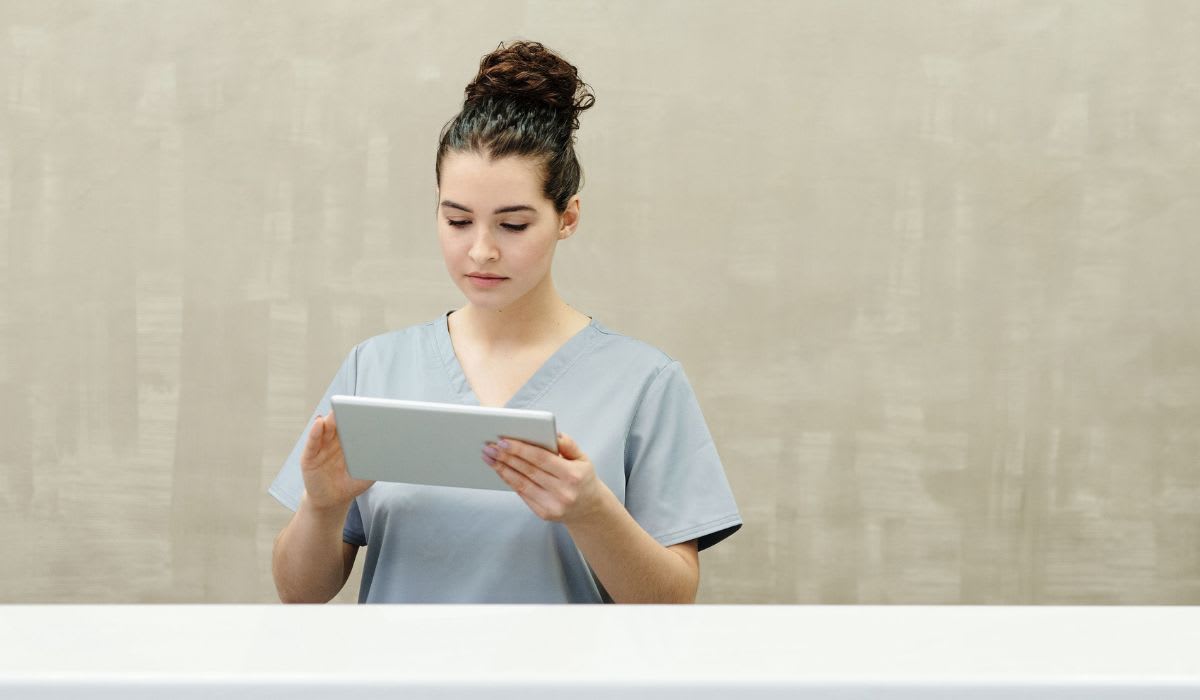 Manicurist in uniform using a tablet at a modern reception desk. (Representative Image Source: Pexels | Cedric Fauntleroy)