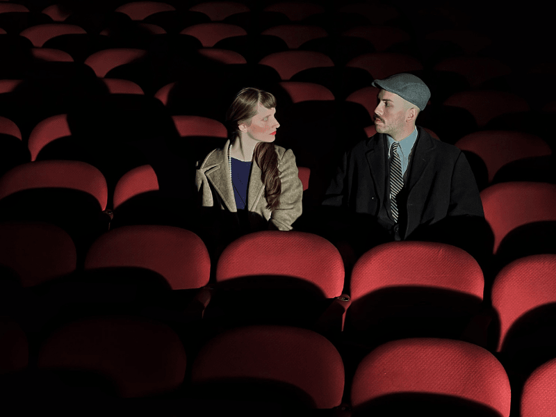 A man and a woman sitting in an empty theatre.